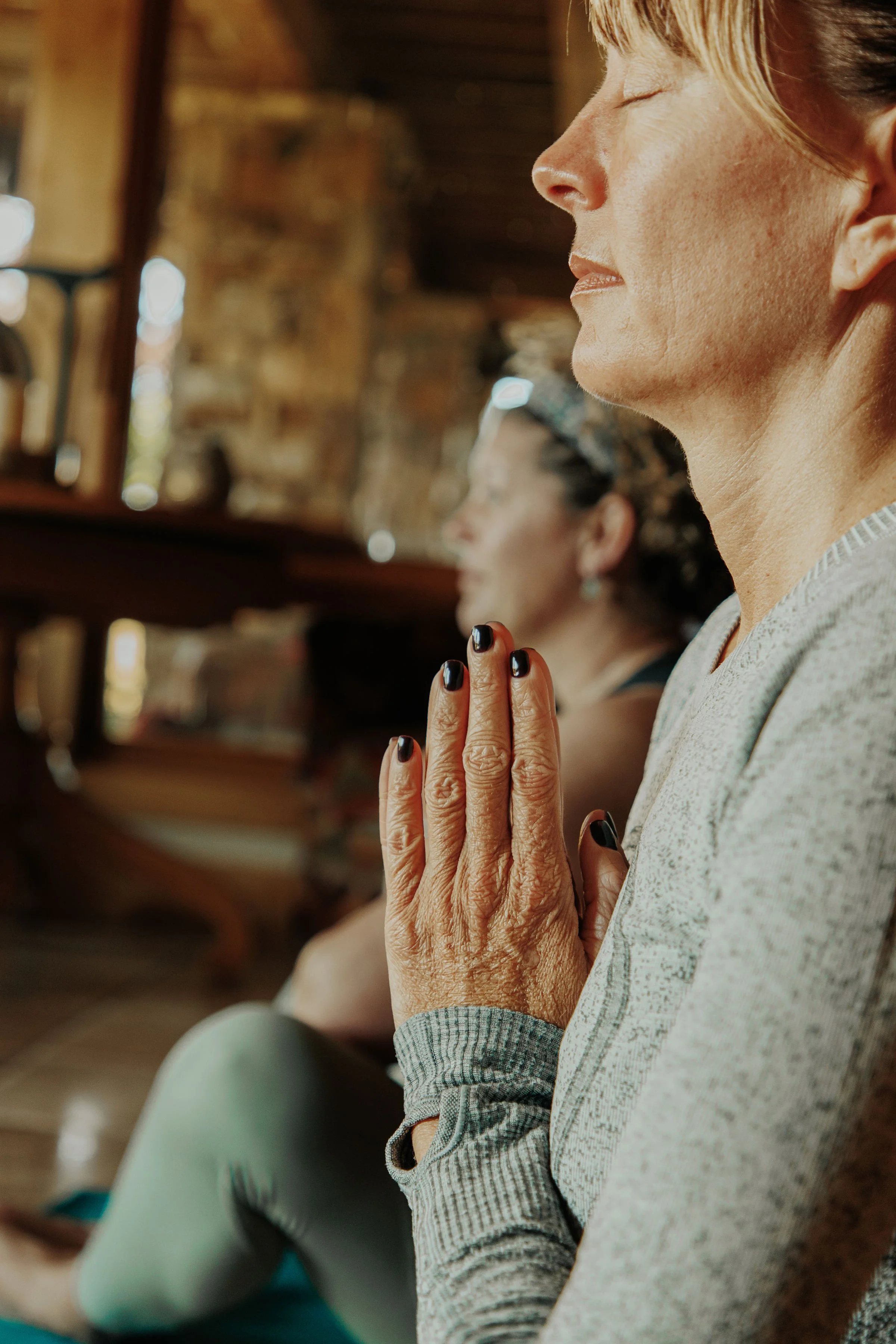 A group of people riding in an open-air train through a scenic rural area with rolling hills, tall grasses, and a partly cloudy sky, all wearing sunglasses and smiling.
