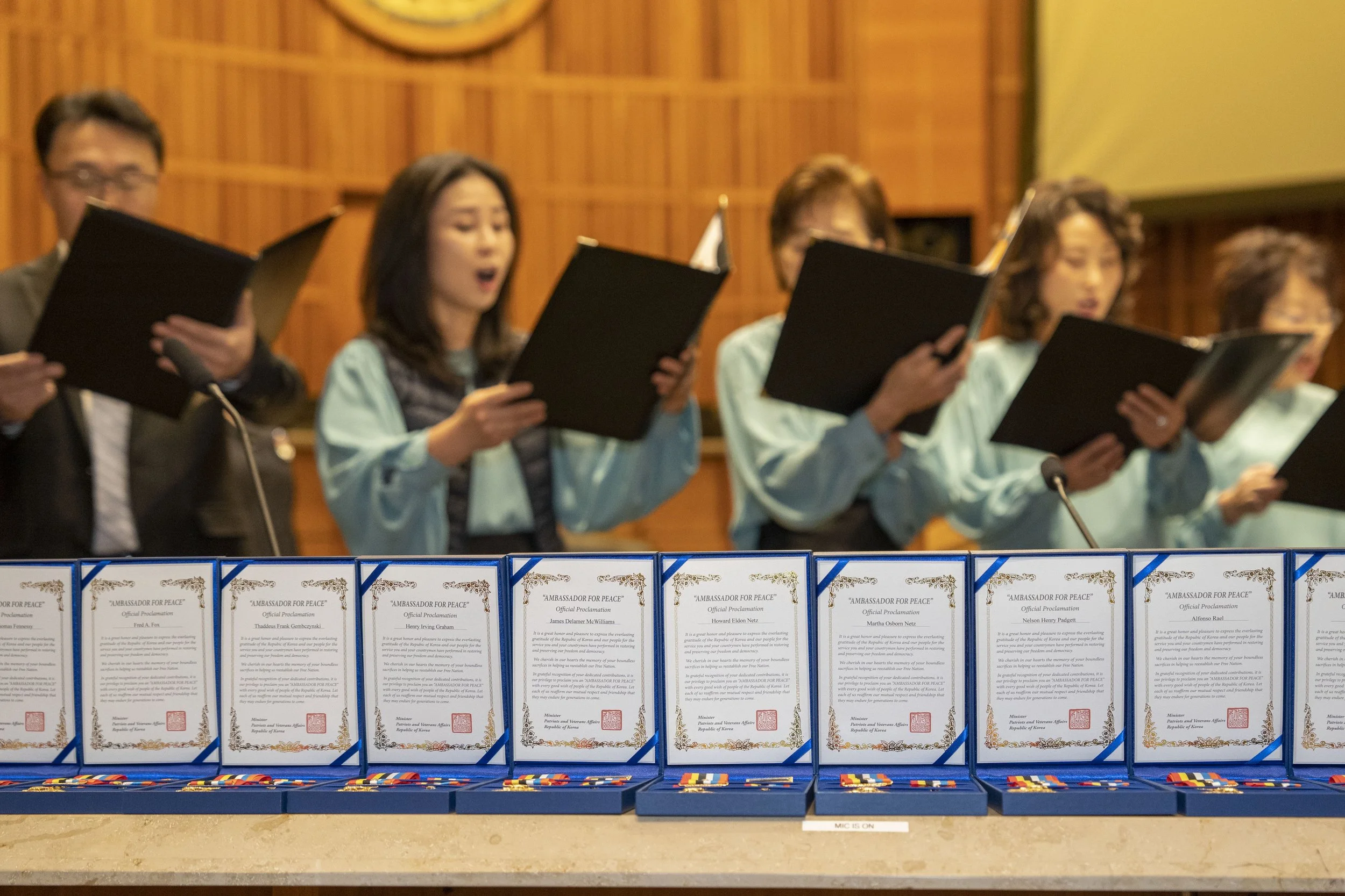 Group of people singing in a choir behind a table with medals and certificates for peace.