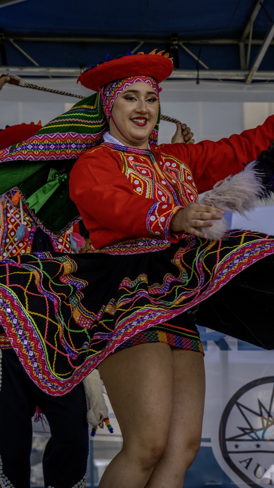 A woman dressed in traditional Mexican folk attire, smiling while participating in a cultural dance performance.