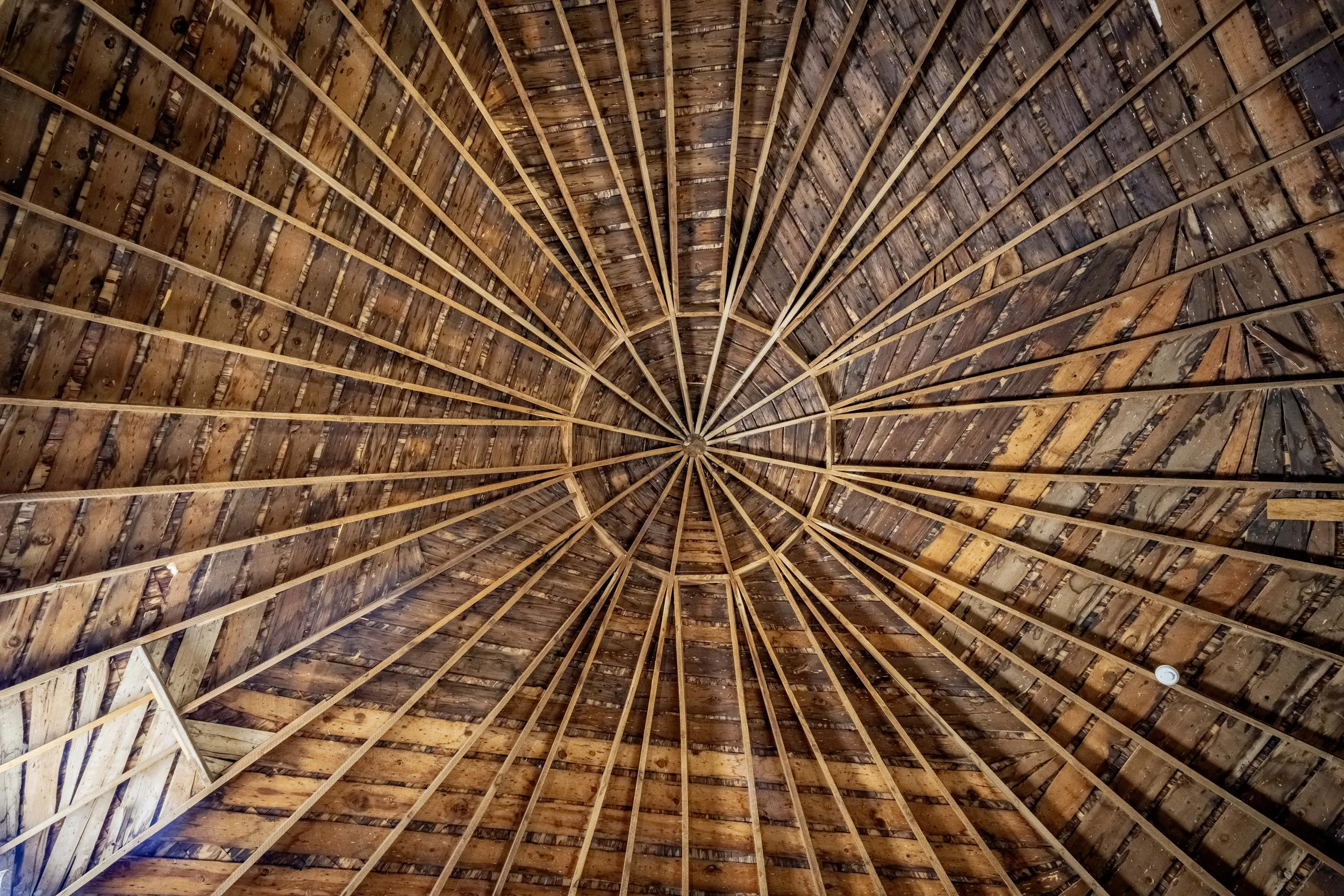 Interior view of a wooden dome ceiling with visible wooden beams converging at the center.