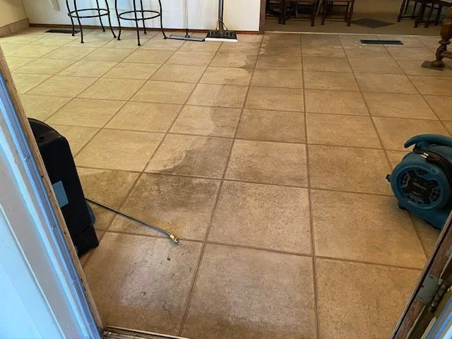 Cleaned tile floor in a room with some cleaning equipment, including a floor cleaner machine and a mop