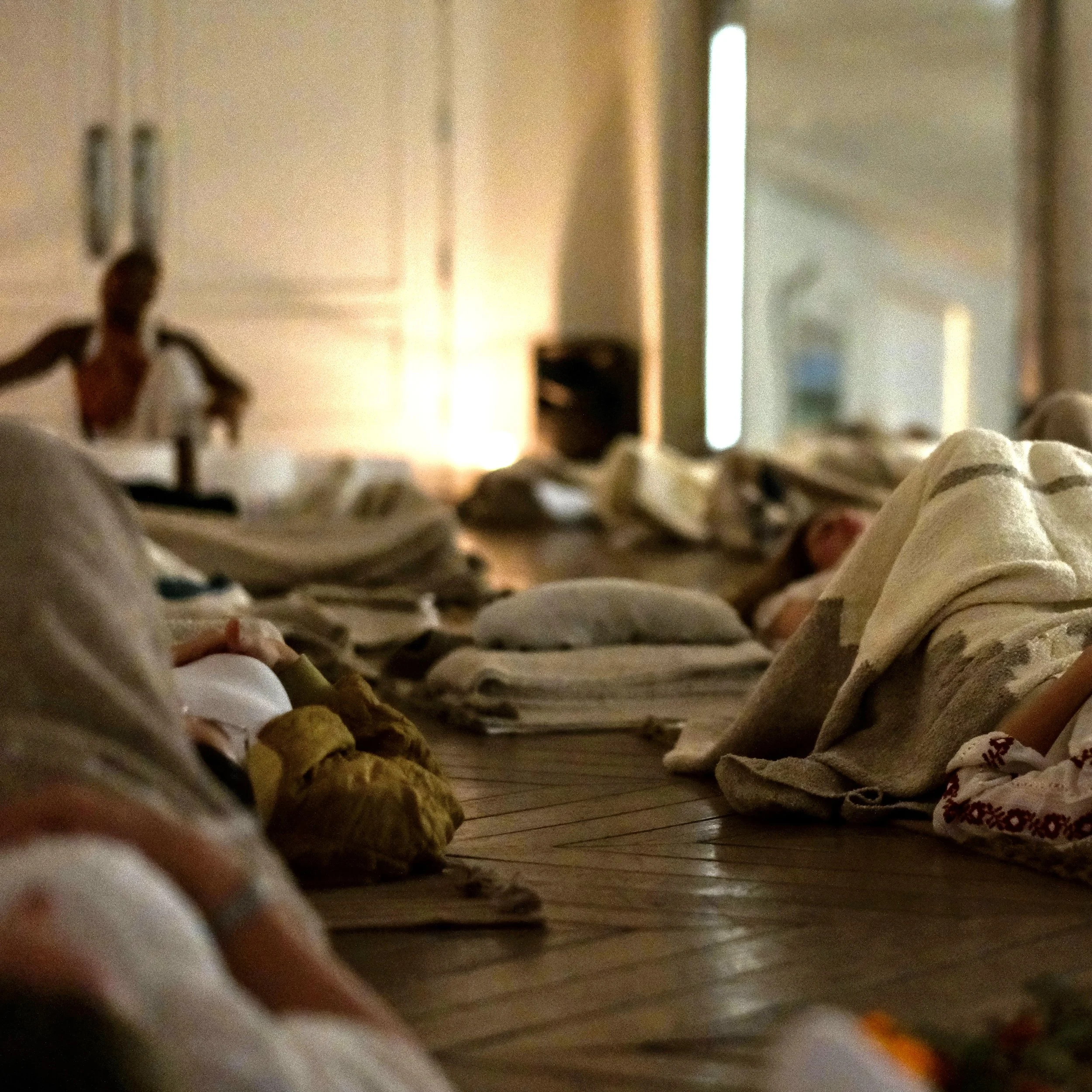 View attendees laying on the ground of a warmly lit room as Onyi Love facilitates a Sound Healing in the background.