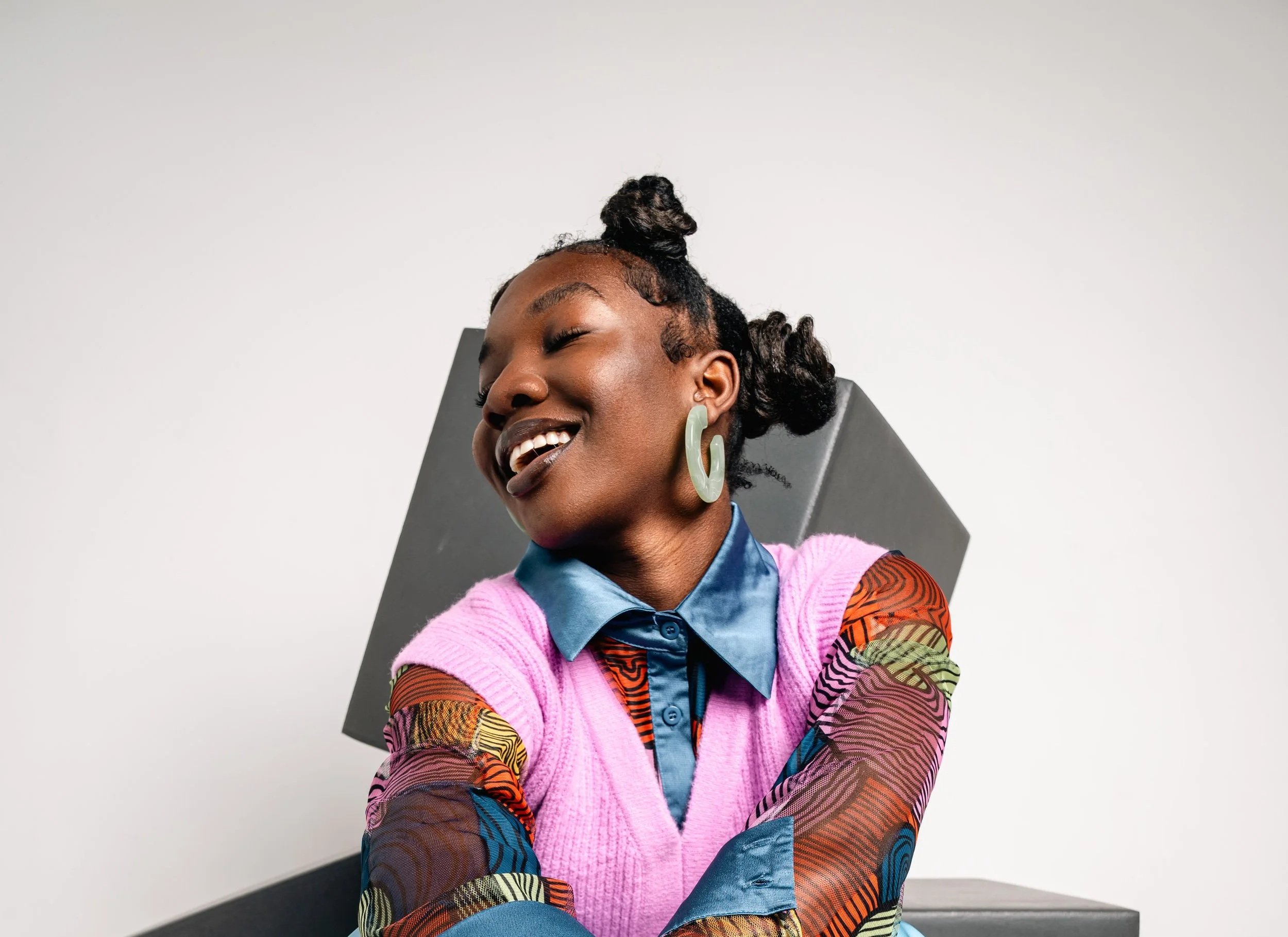 A smiling woman wearing colorful clothes during a creative session at Elle Studios, a playful boutique event venue and photo studio rental space in Bushwick, Brooklyn, NYC.