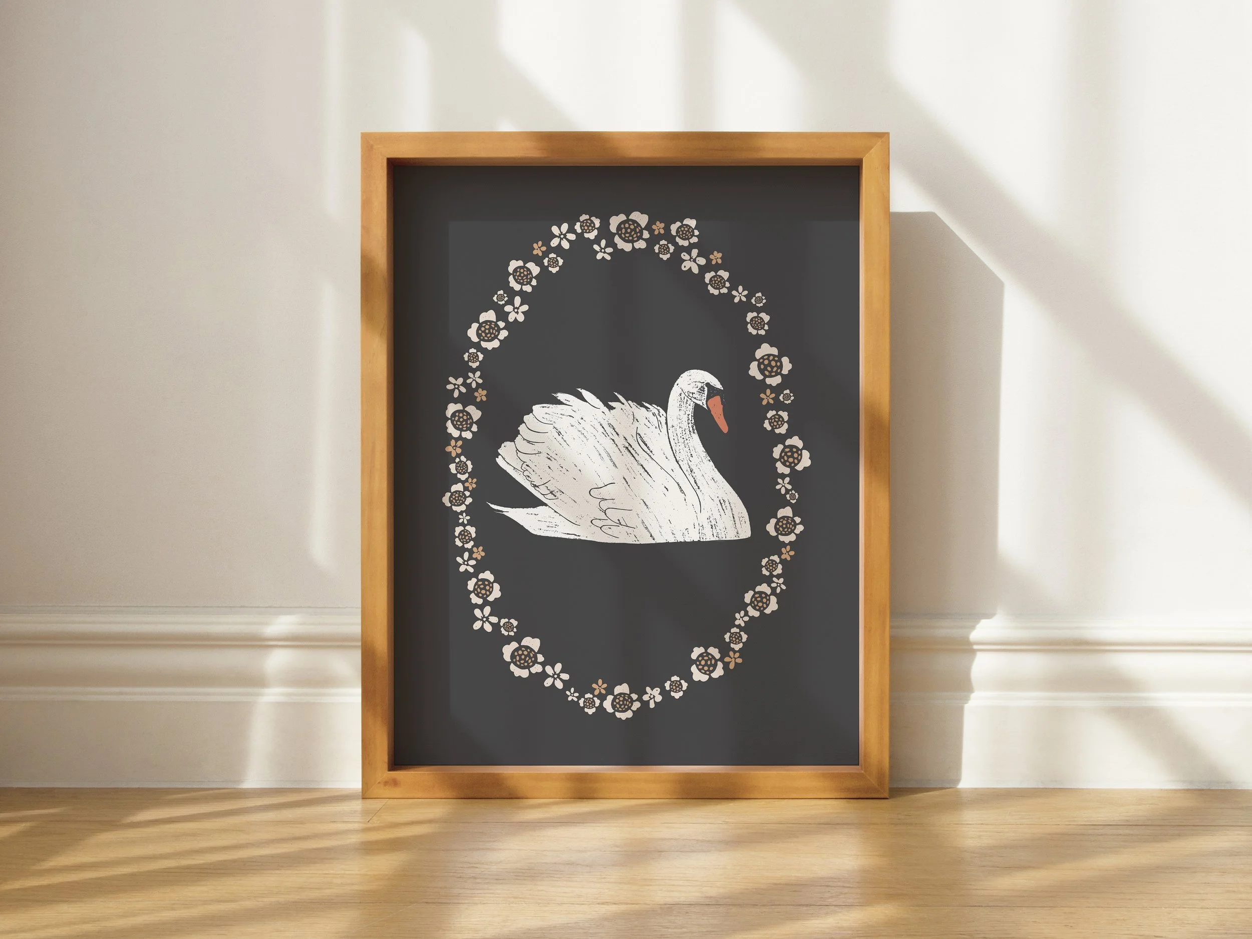 Framed blackboard with a white swan illustration and a floral border, leaning against a light-colored wall with sunlight casting shadows.