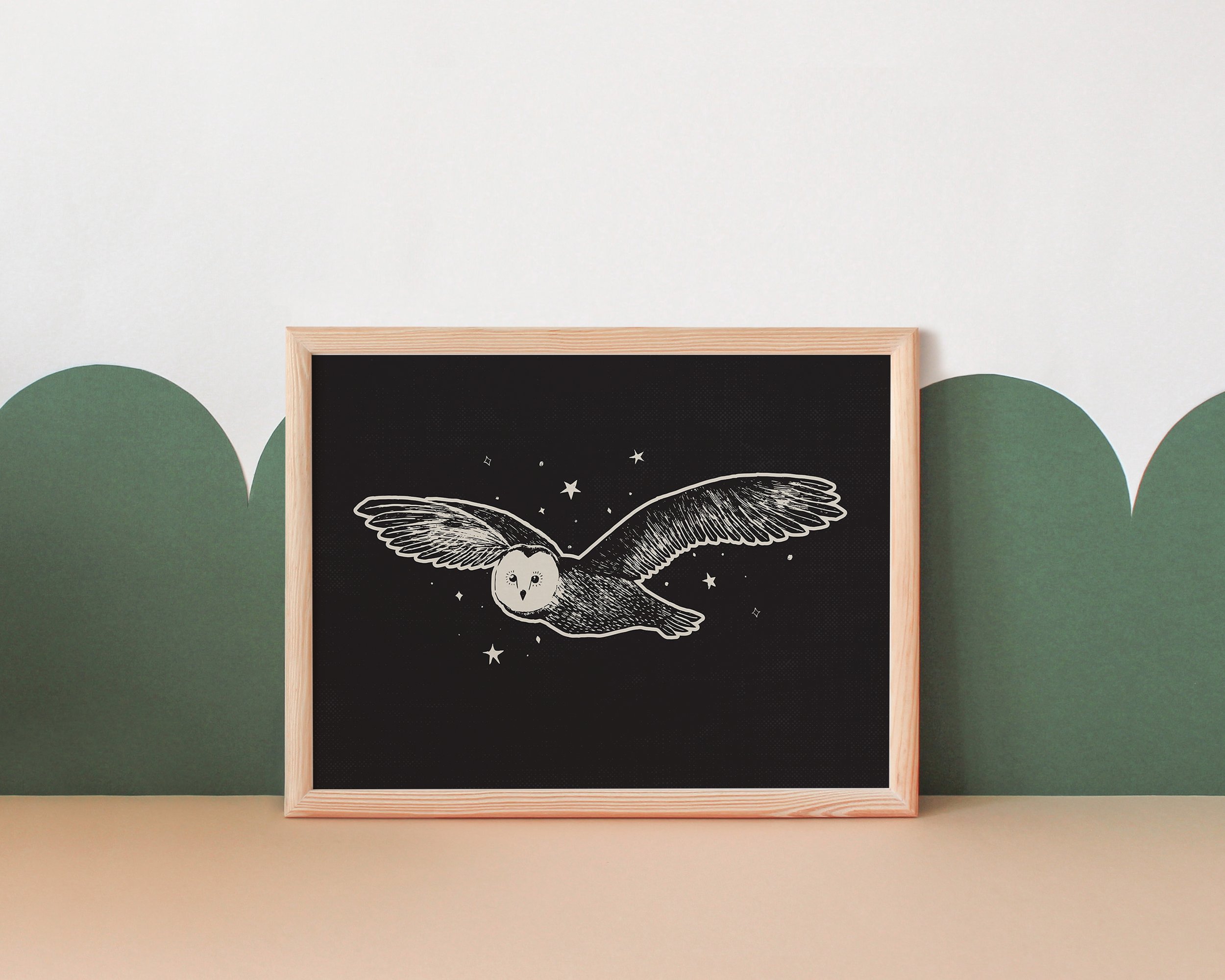 Framed chalkboard drawing of an owl with outstretched wings flying among stars, set against a wall with green mountain-shaped accents.