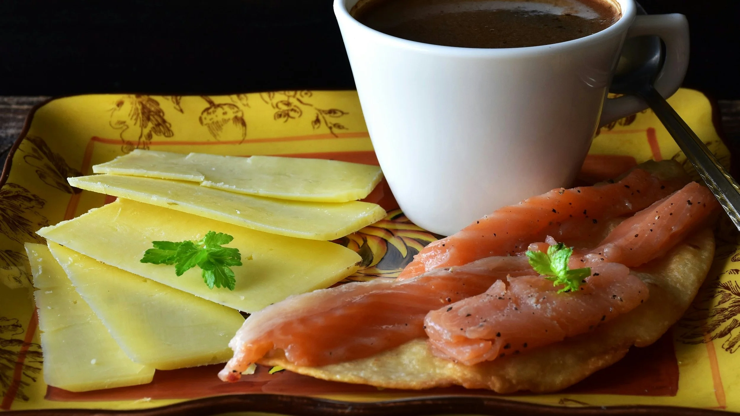 Plate with smoked salmon, cheese slices, and coffee.