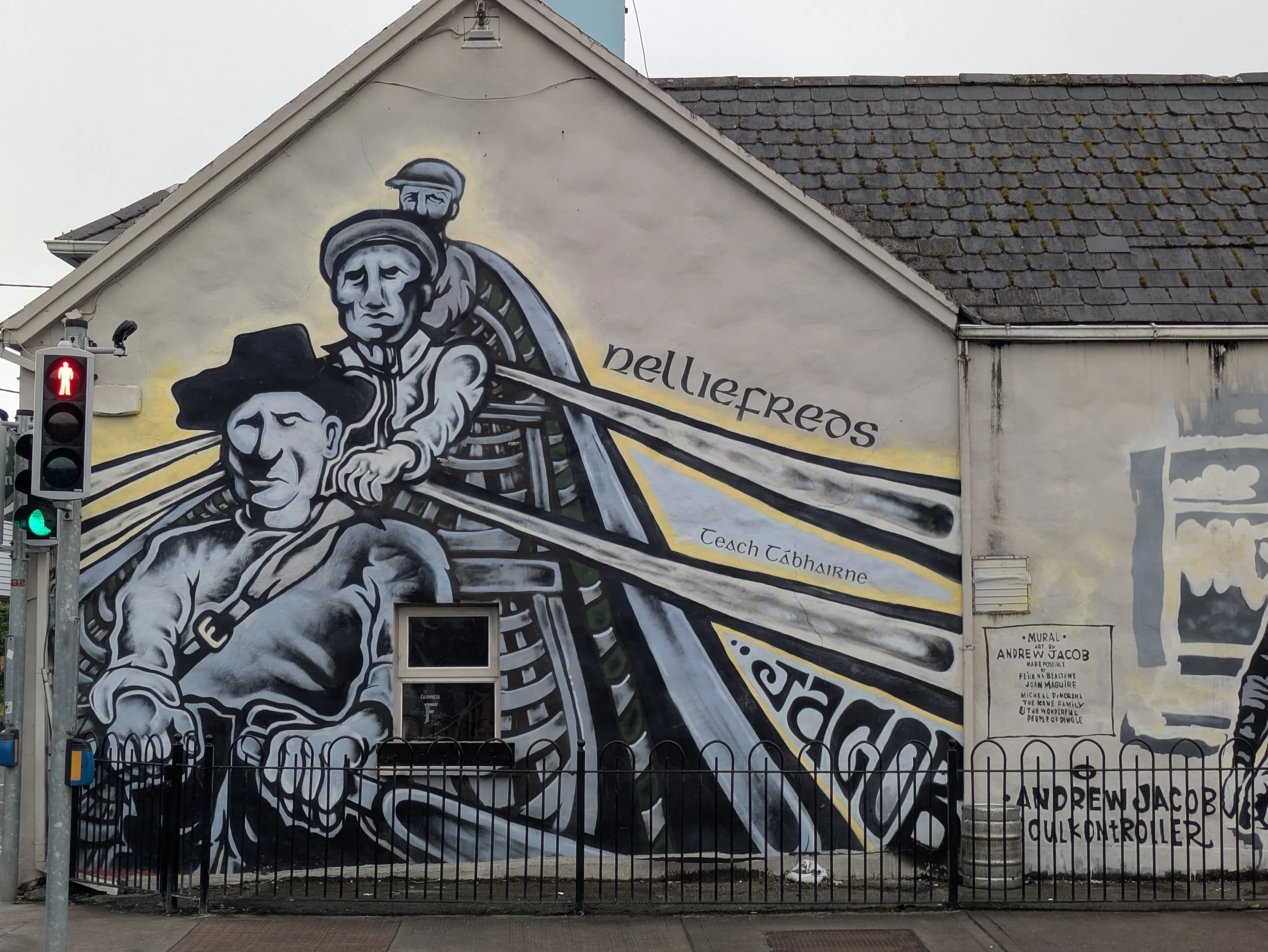 Street mural depicting Irish fishermen rowing, painted on a building in Dingle town.