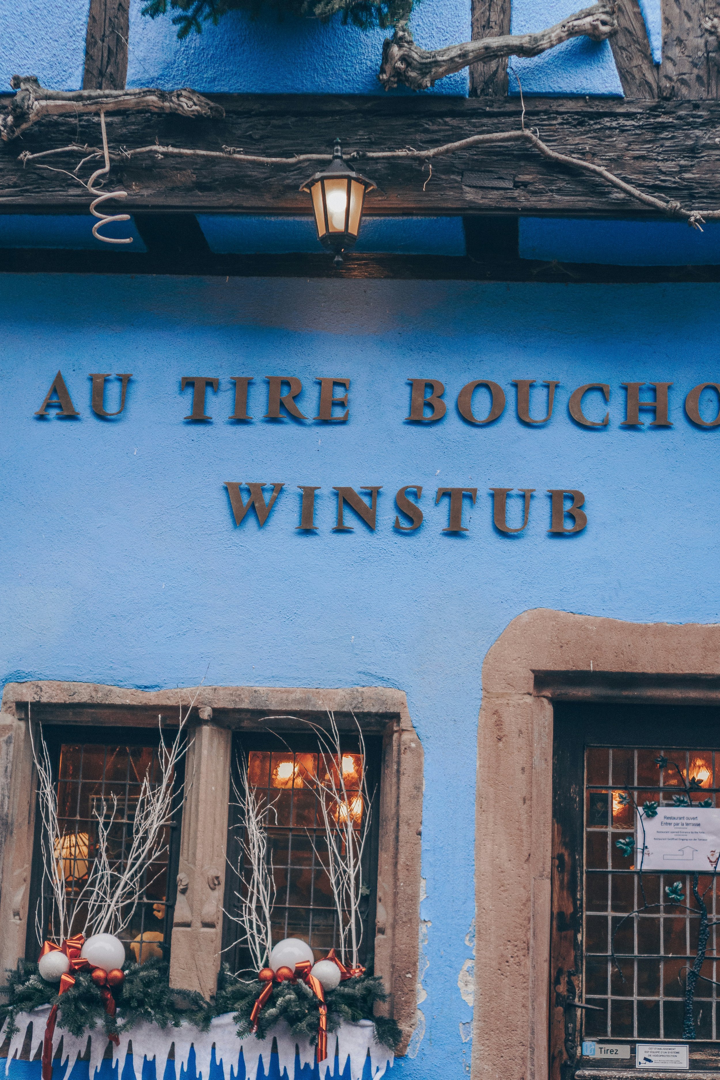 Blue façade of a traditional winstub restaurant decorated for winter.
