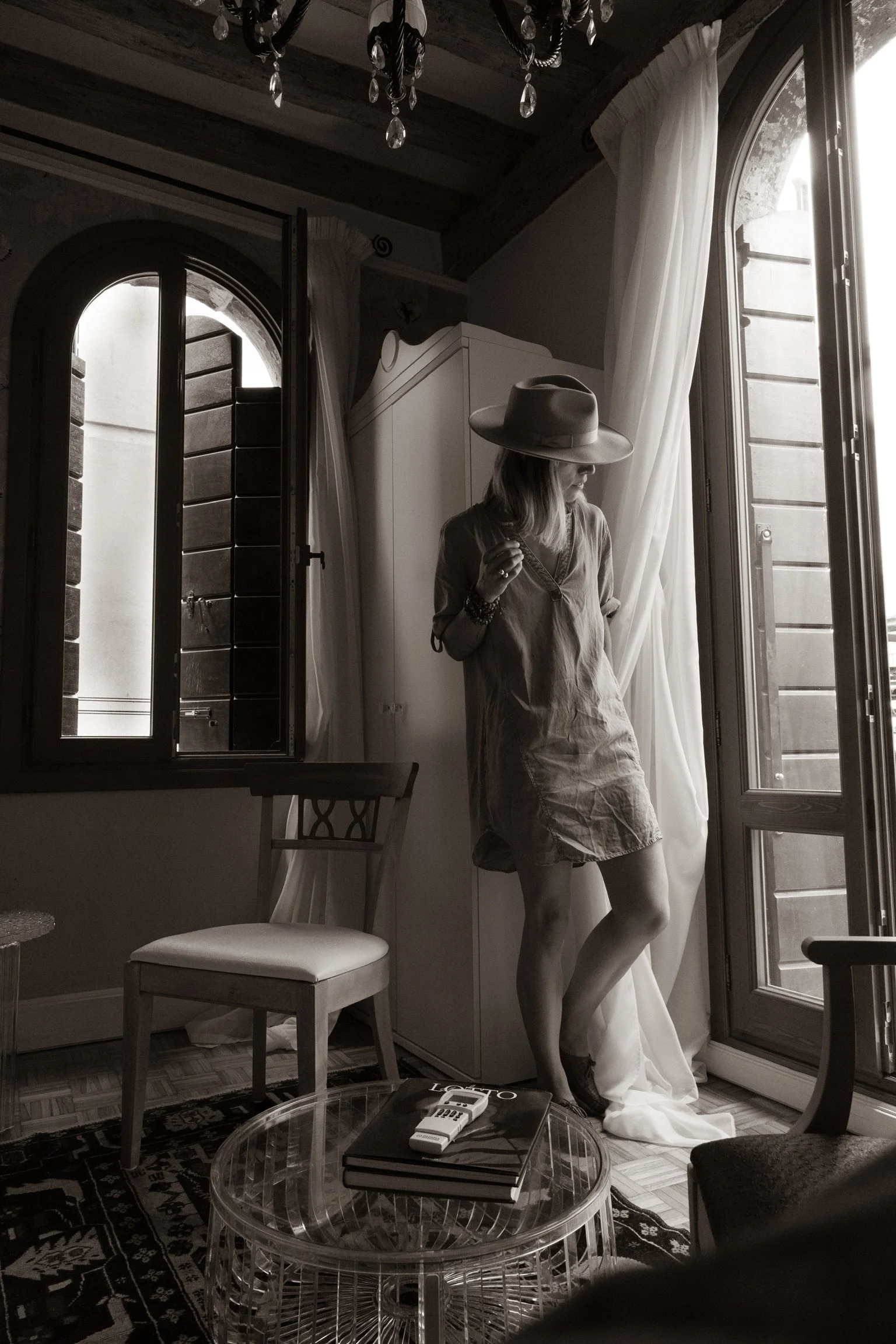 a woman of timeless beauty peering out the floor to ceiling window of a loft in Venezia