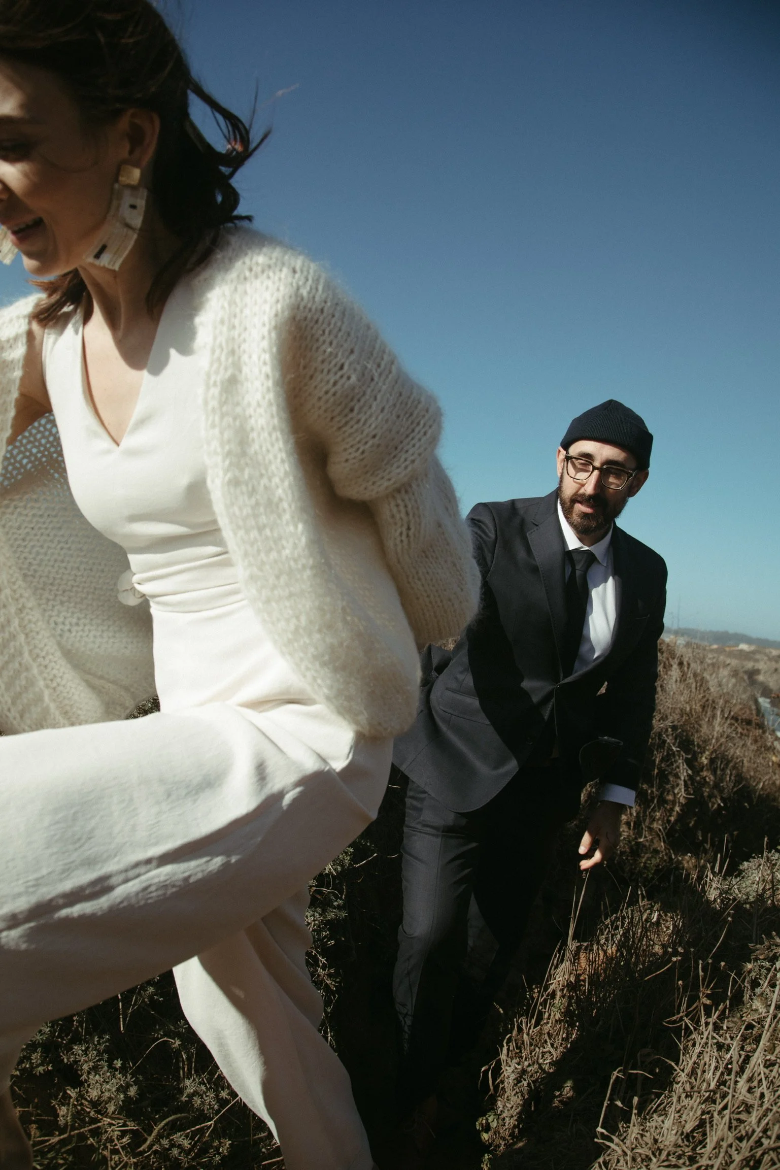 Woman in white outfit and man in suit climbing hill