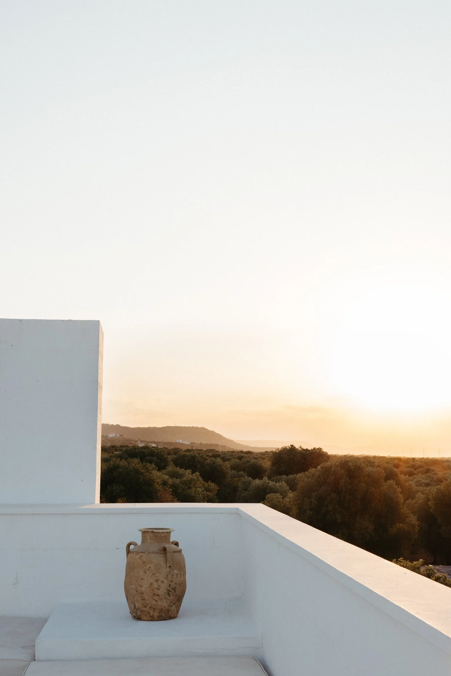 Terracotta pot on white terrace with sunset view over a landscape of vineyards