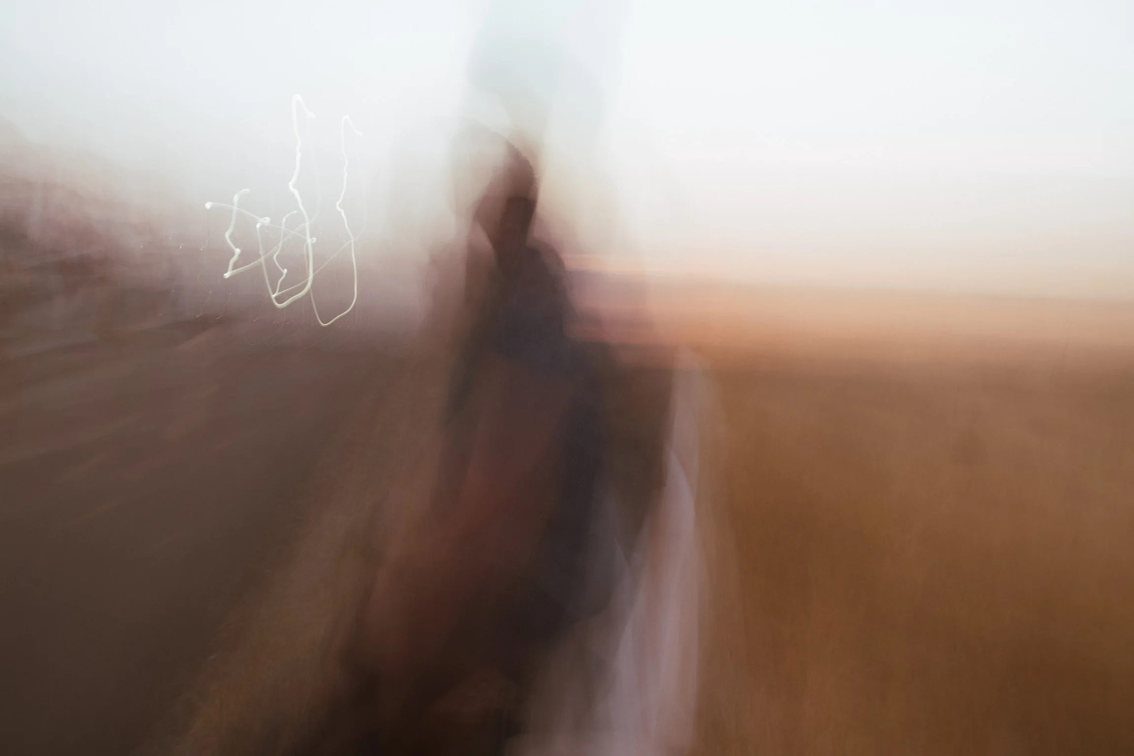 an abstract, dreamy image capturing a couple at dusk as they travel across grasslands