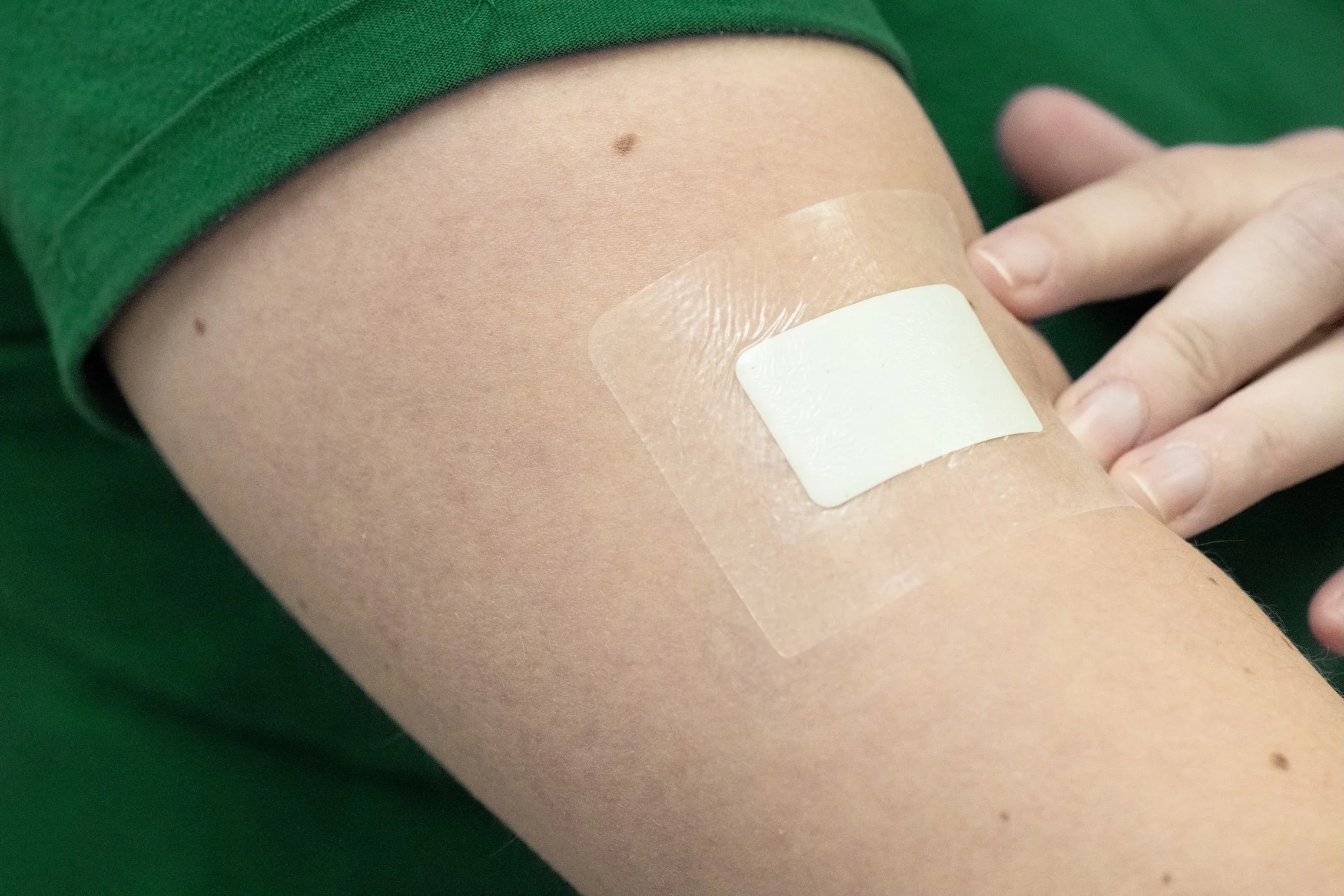A person's arm with a medical bandage or adhesive bandage on it, being prepared for a blood draw or injection.