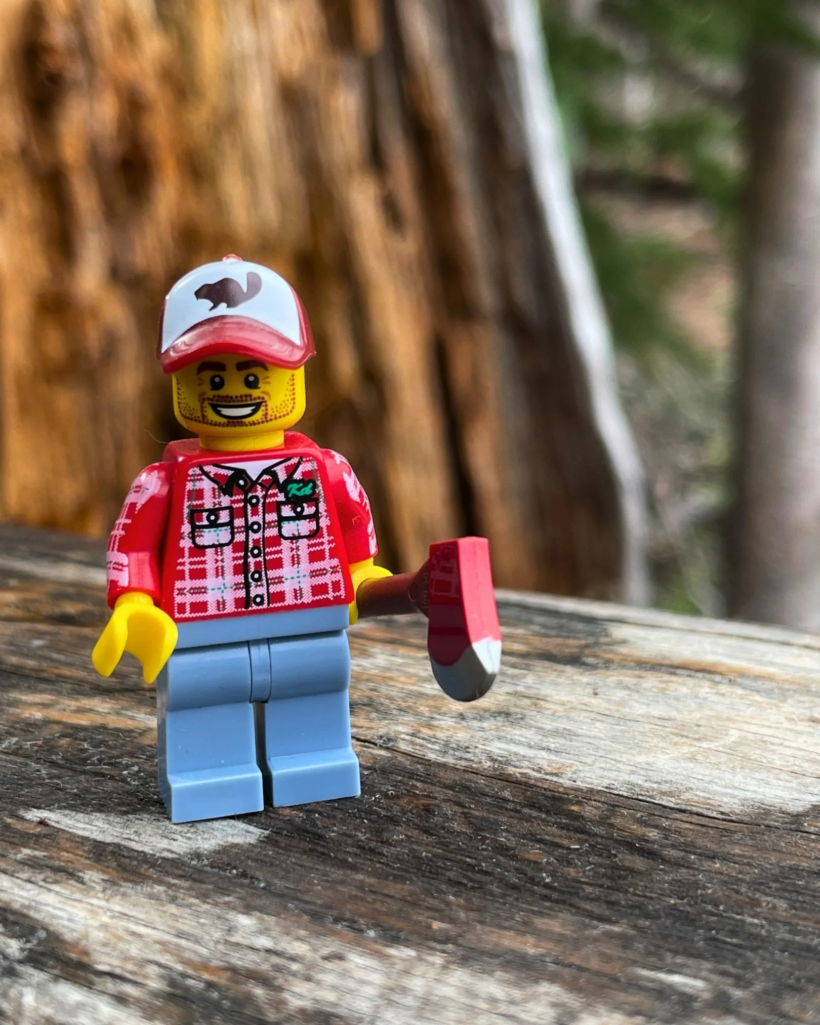 LEGO lumberjack minifigure holding an axe while standing on a fallen log in the forest, celebrating playful outdoor adventures and imagination.