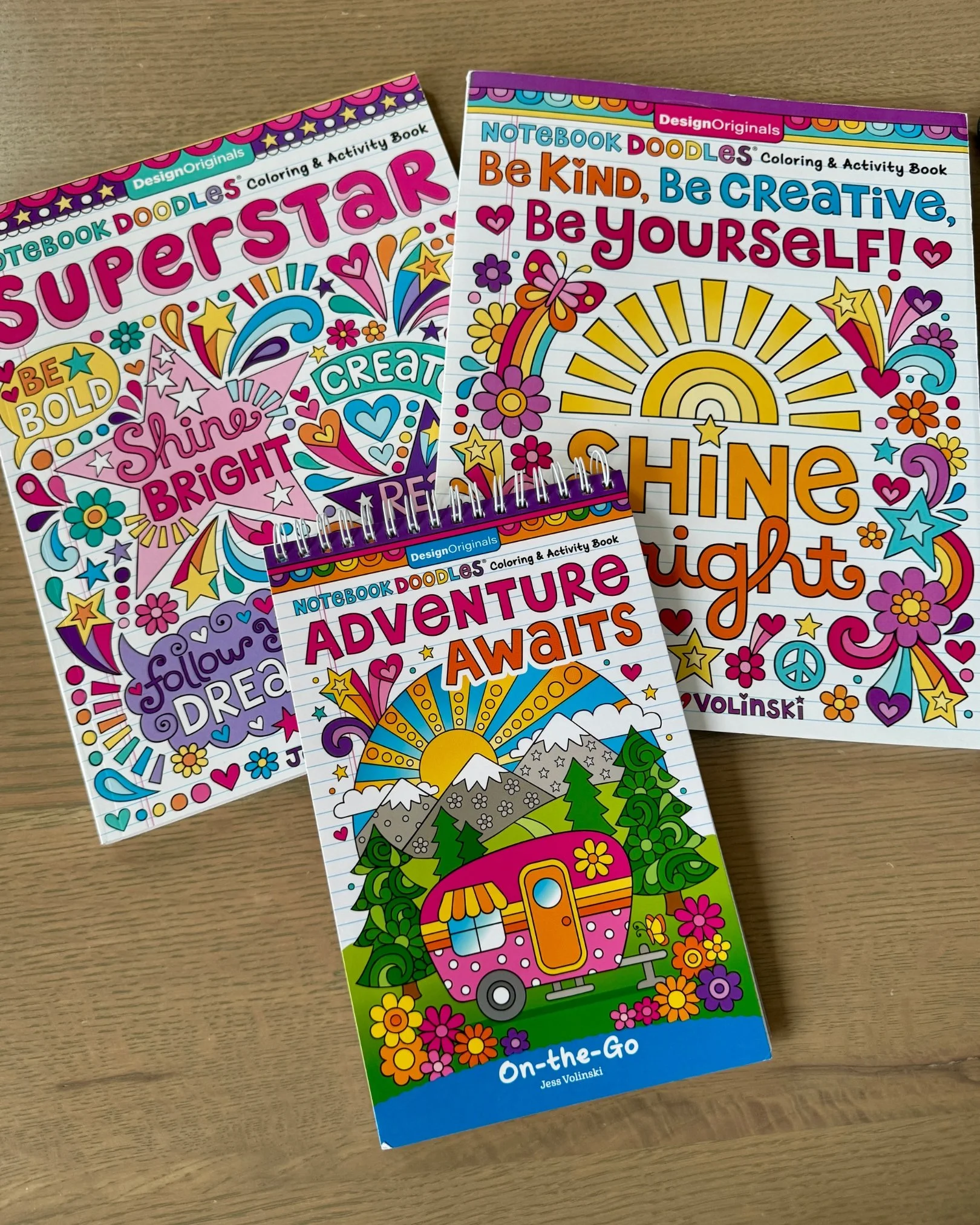 Brightly colored creativity and doodle-themed coloring books and activity pads arranged on a table.
