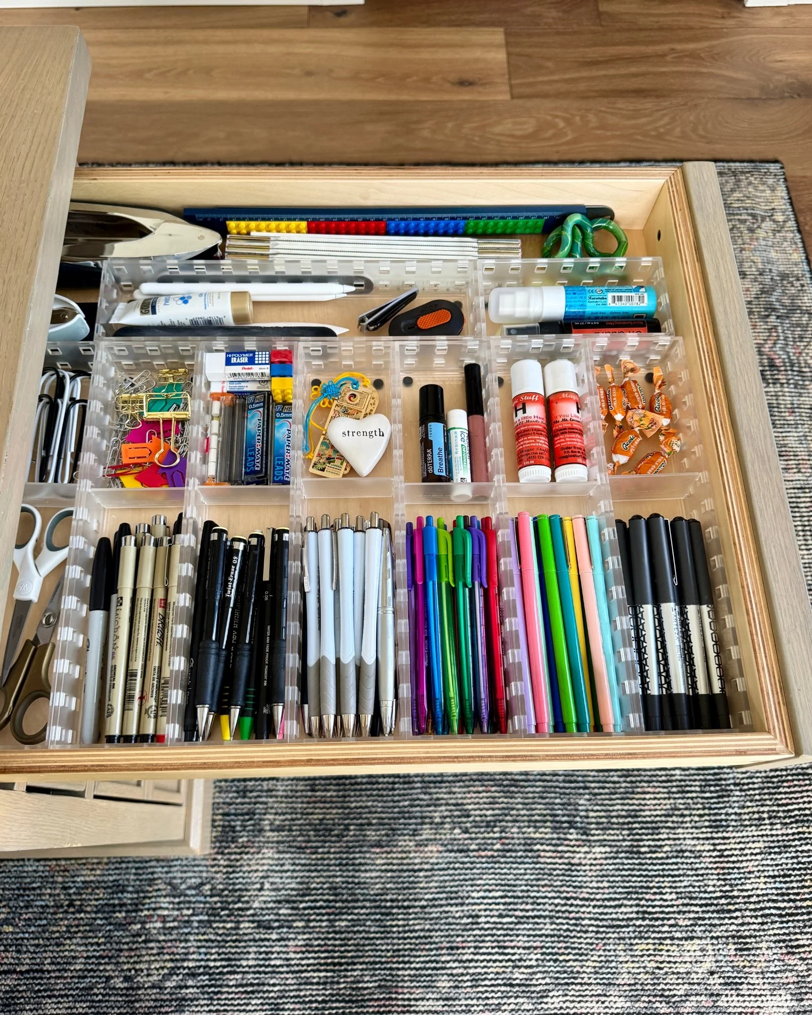 Organized drawer filled with pens, markers, scissors, clips, and creative supplies sorted into clear containers.