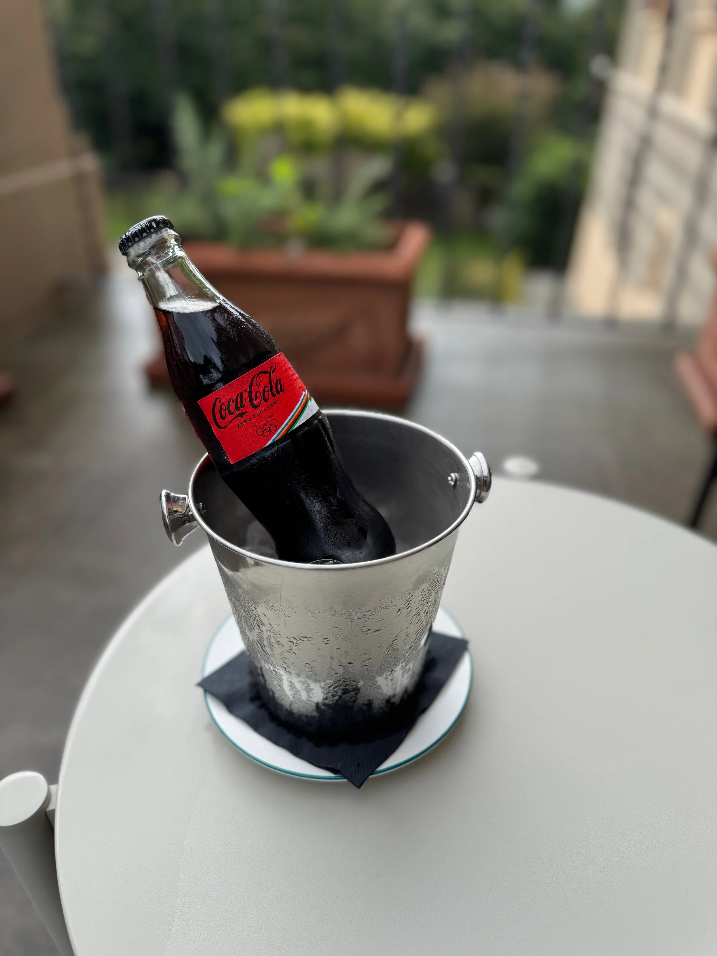 Bottle of Coca-Cola served in an ice bucket on an outdoor café table in Perugia, Italy.
