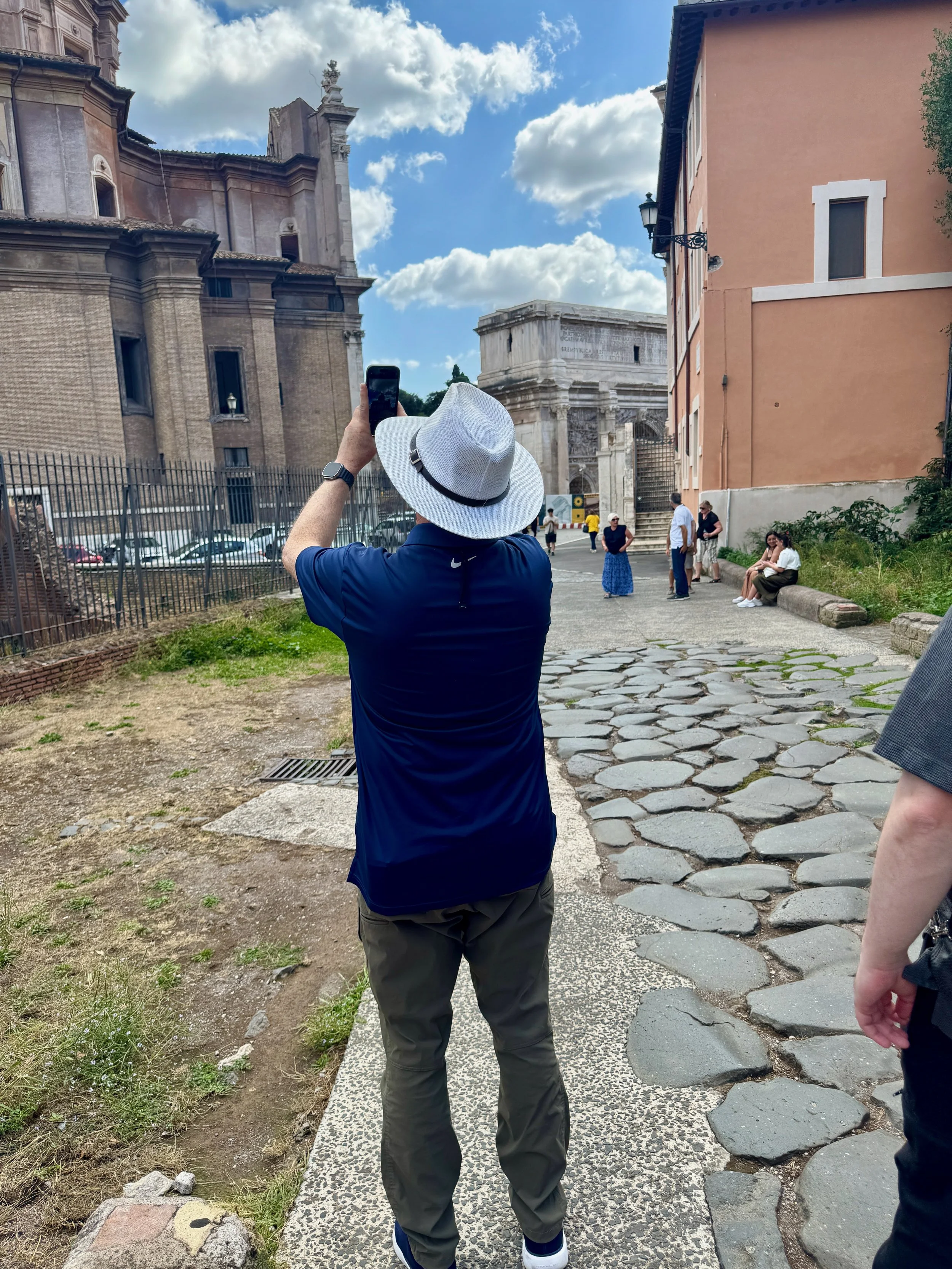 a photograph of a tourist taking a picture of Roman ruins