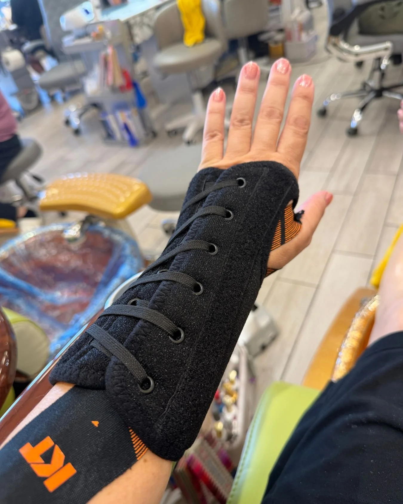 Hand and wrist in a black lace-up brace during a manicure appointment, documenting a health-related part of everyday life.