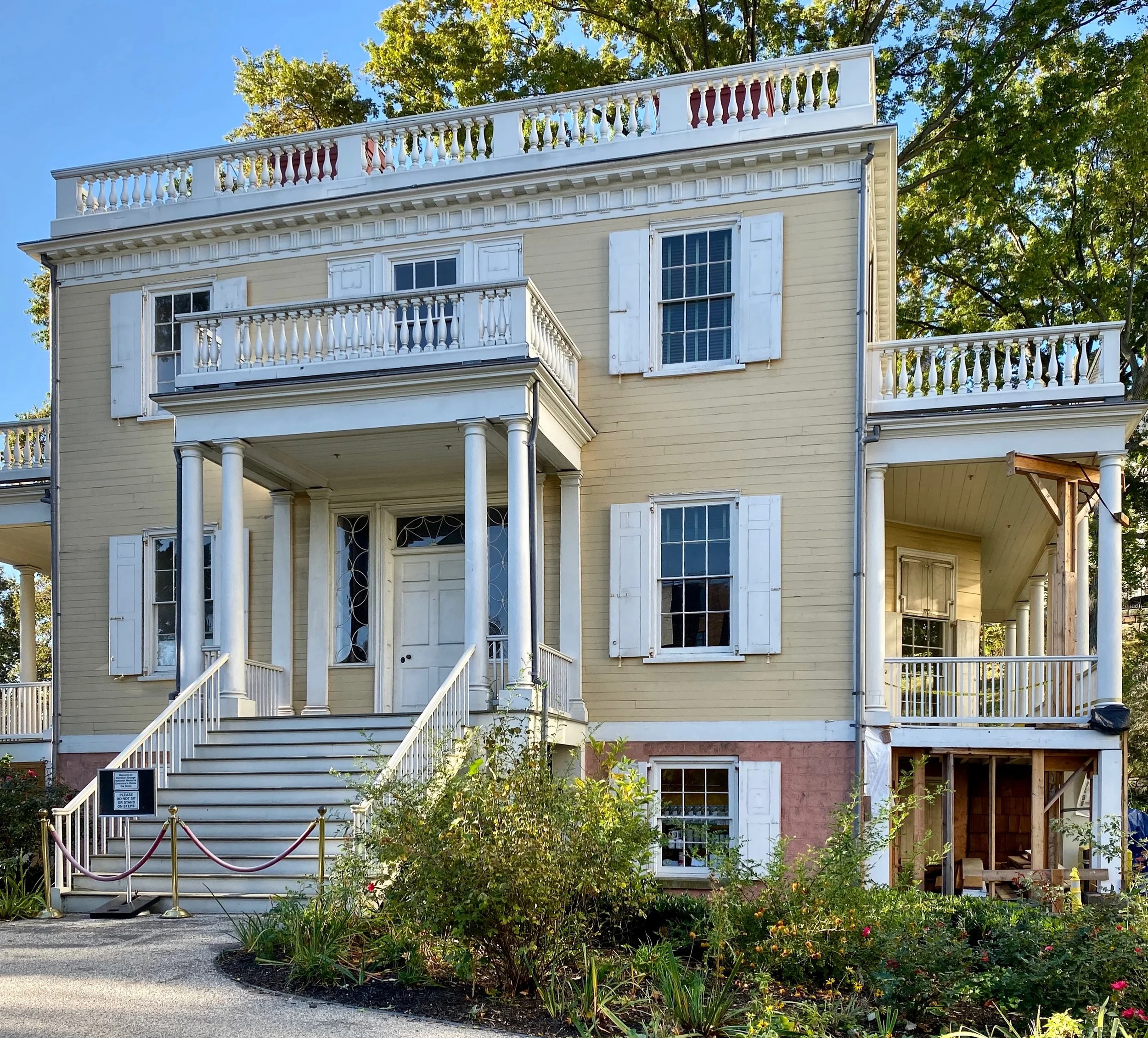 Historic home of Alexander Hamilton surrounded by trees and gardens on a sunny day.