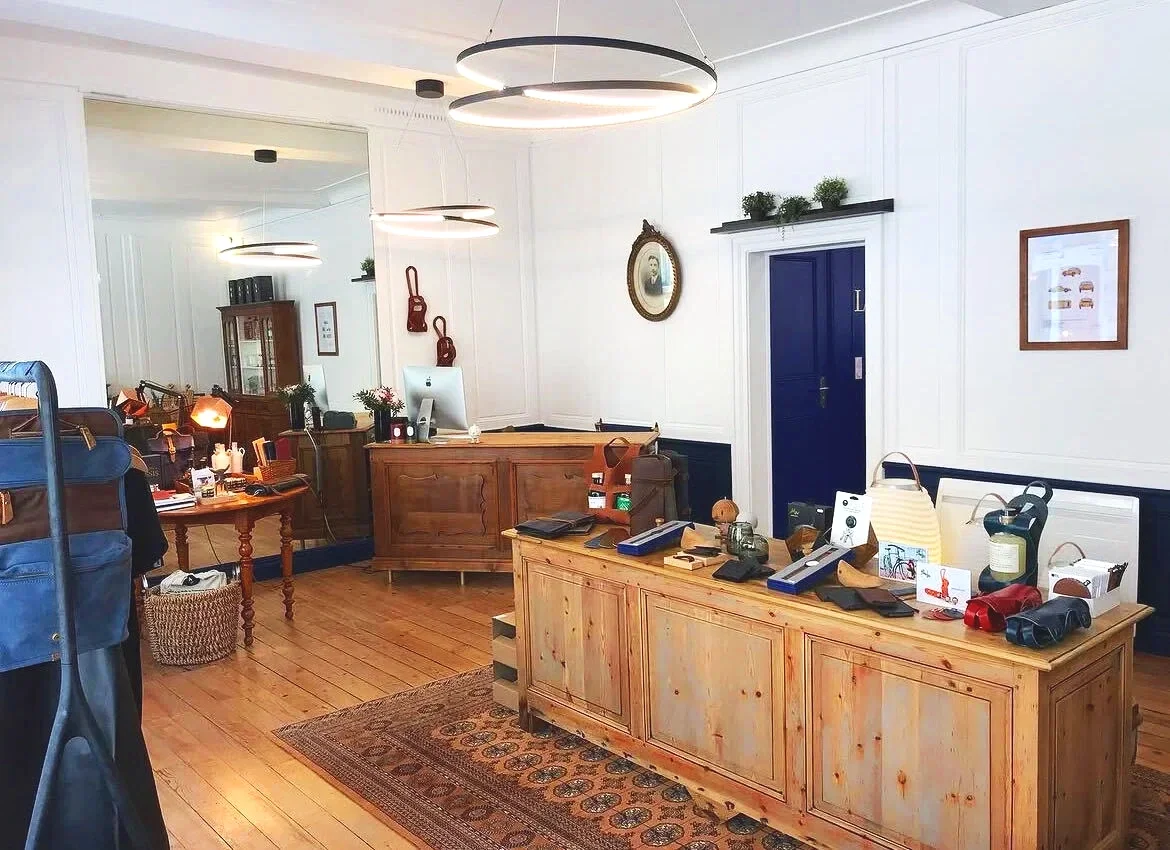 Un bureau de caisse avec un mobilier en bois, des lampes modernes, des décorations murales, et plusieurs objets personnels et professionnels sur la table.