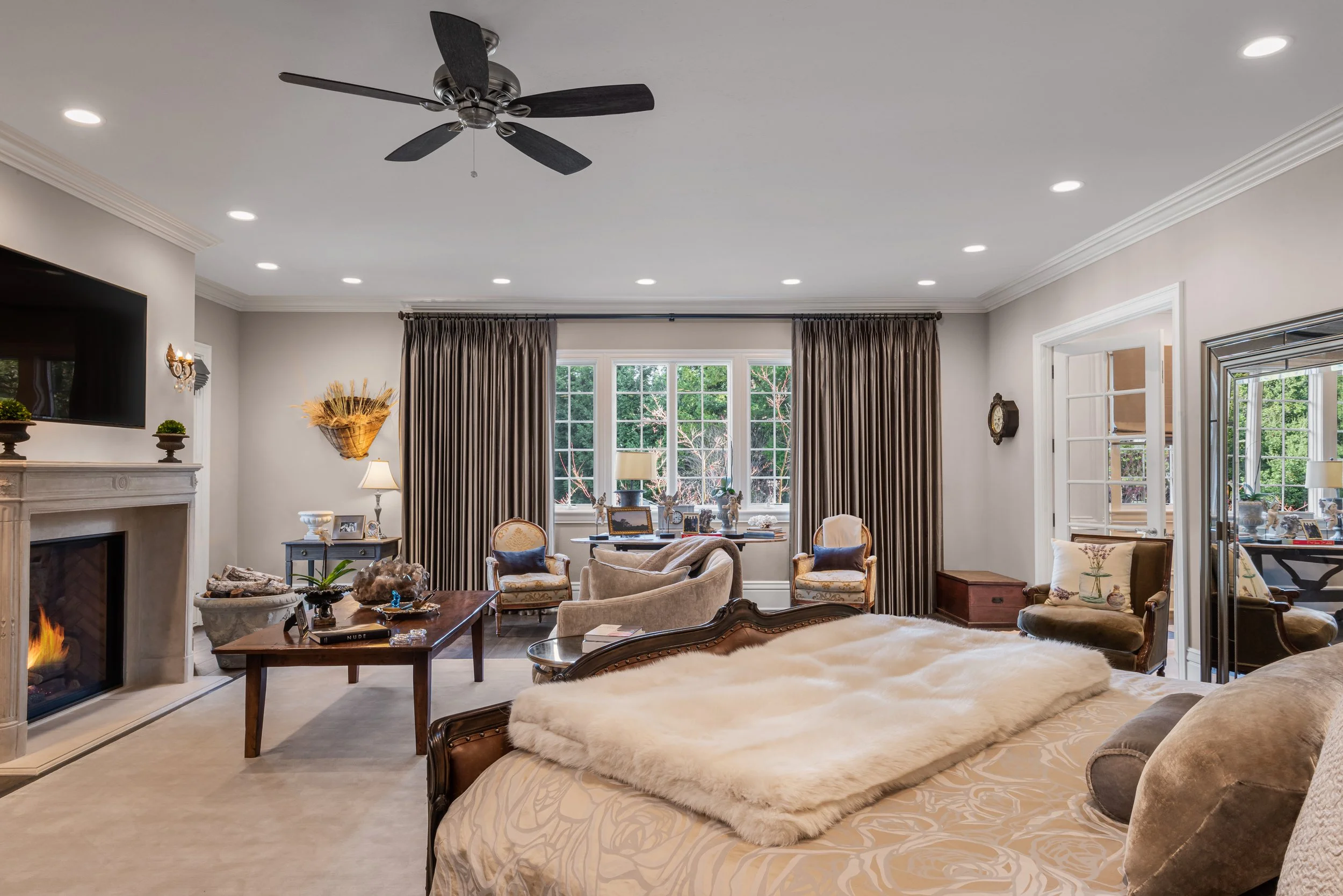 Spacious living room with a cozy fireplace, large window with curtains, plush furniture, and decorative items.