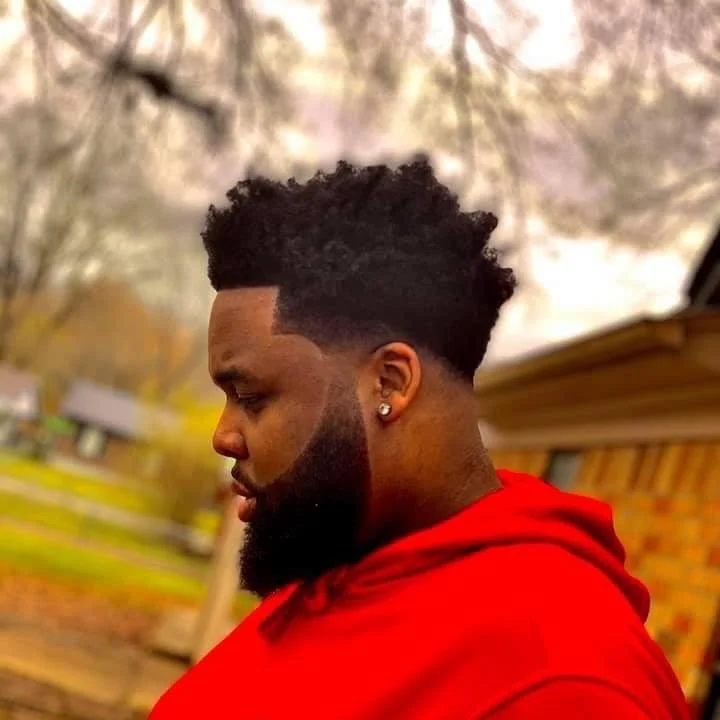 Man with beard and afro hairstyle in red sweatshirt outdoors
