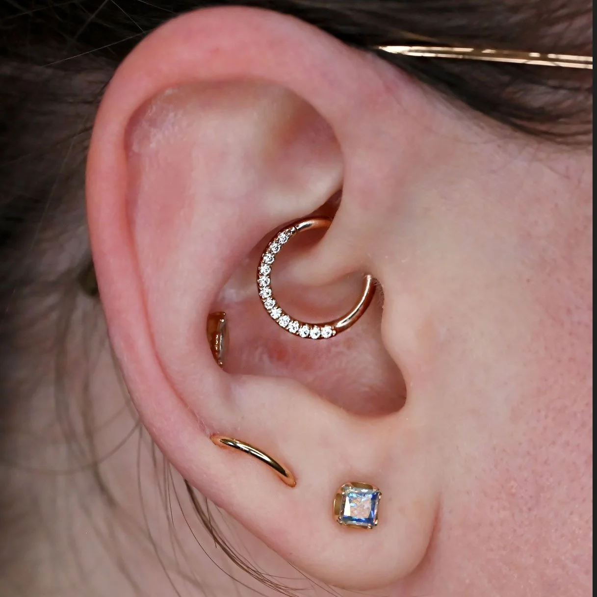 daith piercing pierced by dee at coven body arts with a 14k solid yellow gold ring from junipurr body jewelry. ear piercing pierced with a ring with gems professionally pierced in calgary, alberta. orbital lobe piercing pierced by dee with a 14k gold