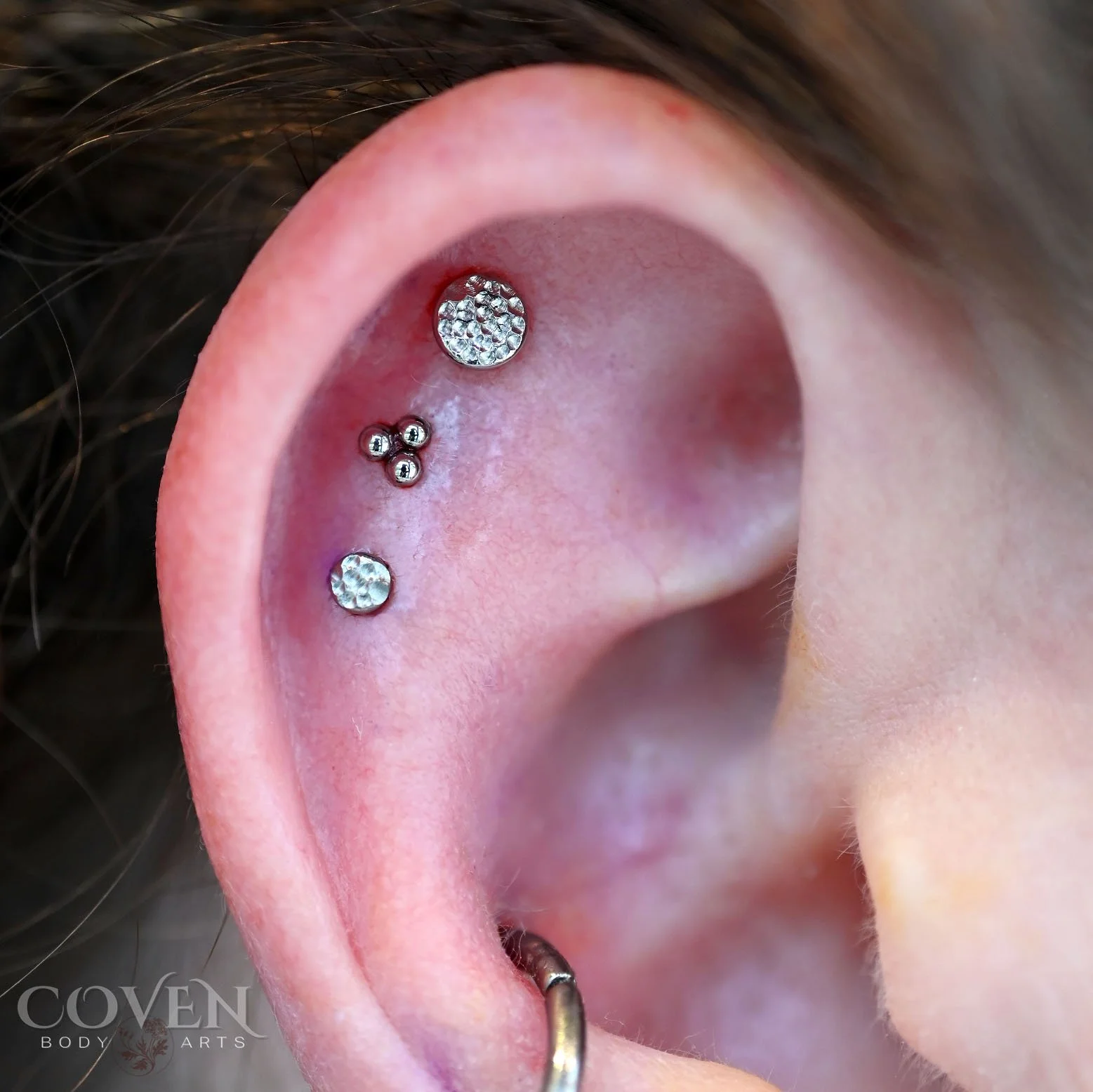 Triple flat piercings performed by Dee at Coven Body Arts, a professional body piercing studio in Calgary, Alberta, Canada.
Three perfectly aligned flat piercings with 2 different sized titanium textured disks from People's Body Jewelry and a titaniu