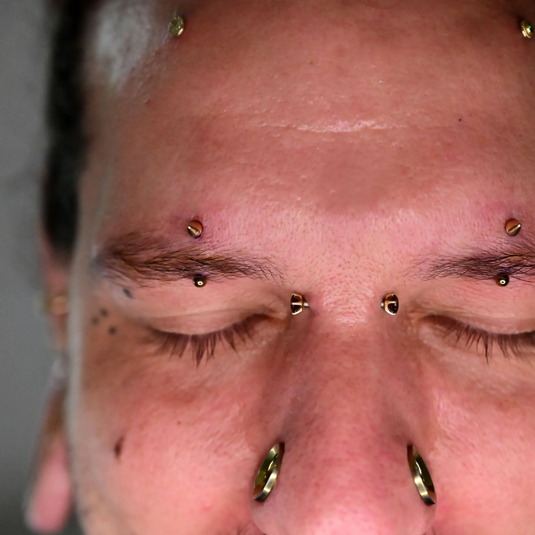 double eyebrow piercings performed by a professional body piercer. male wearing 14k solid gold yellow spikes on a titanium curved barbell. matching eyebrow piercings performed in a professional body piercing studio in calgary, alberta. man wearing cu