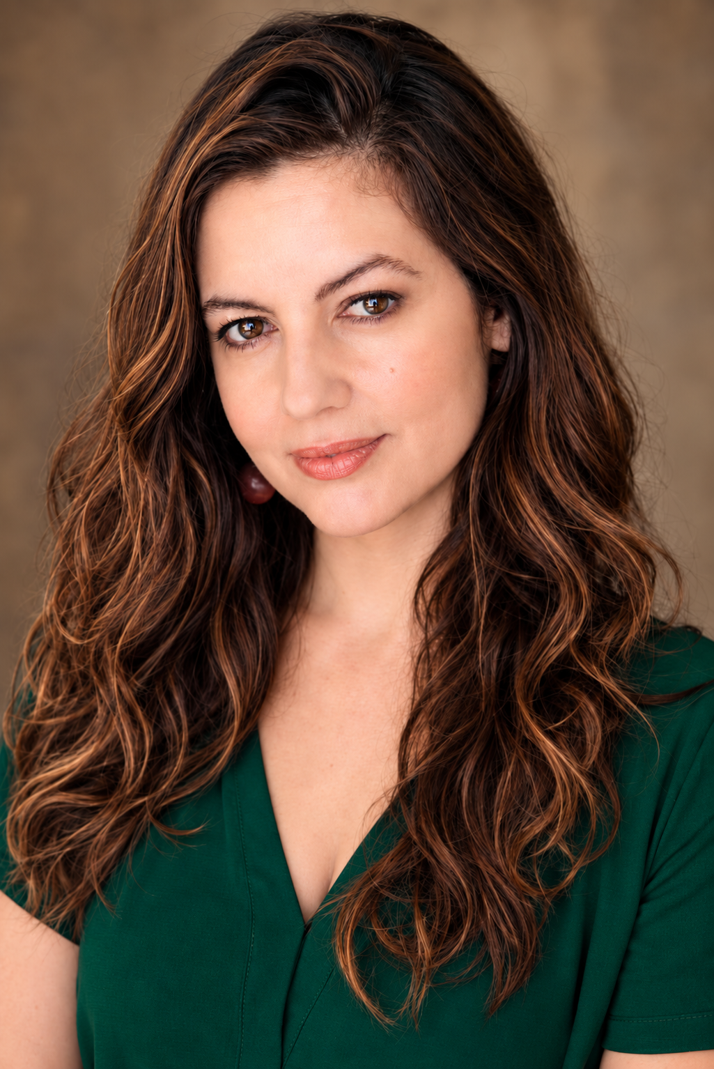 Actress Lorena Fernández in an emerald-green top, looking directly at the camera in a professional theatrical headshot.