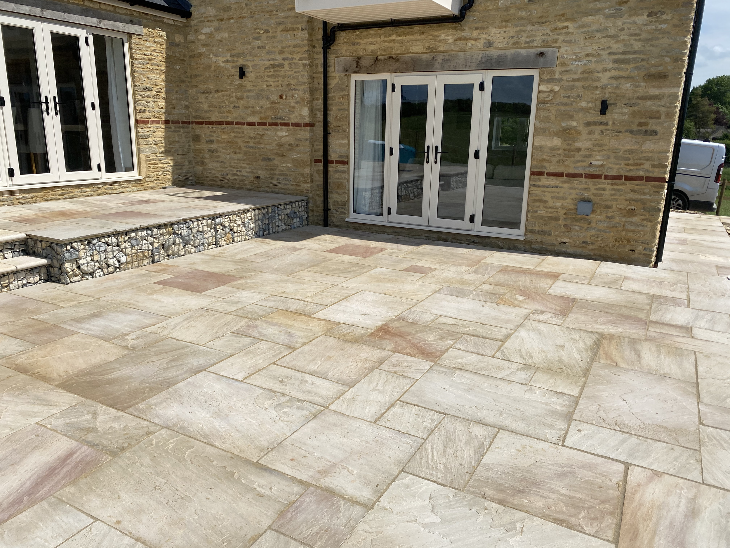 Stepped sandstone patio with gabions in Leafield, Witney