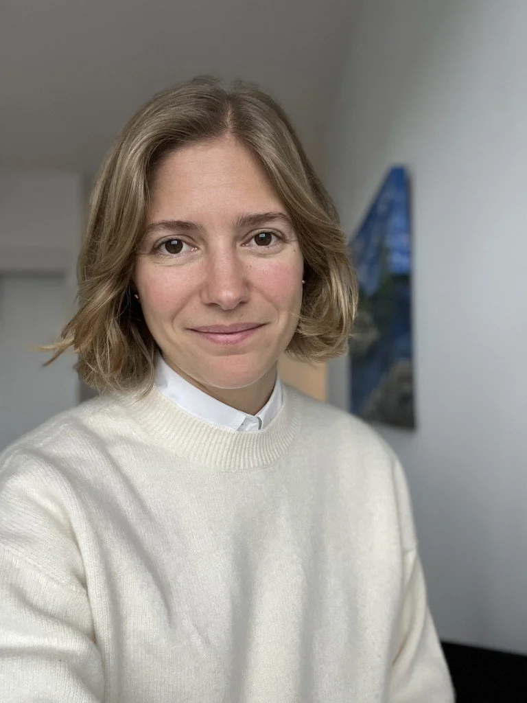 image: blonde female therapist wearing a beige sweater looking at the camera with a warm smile