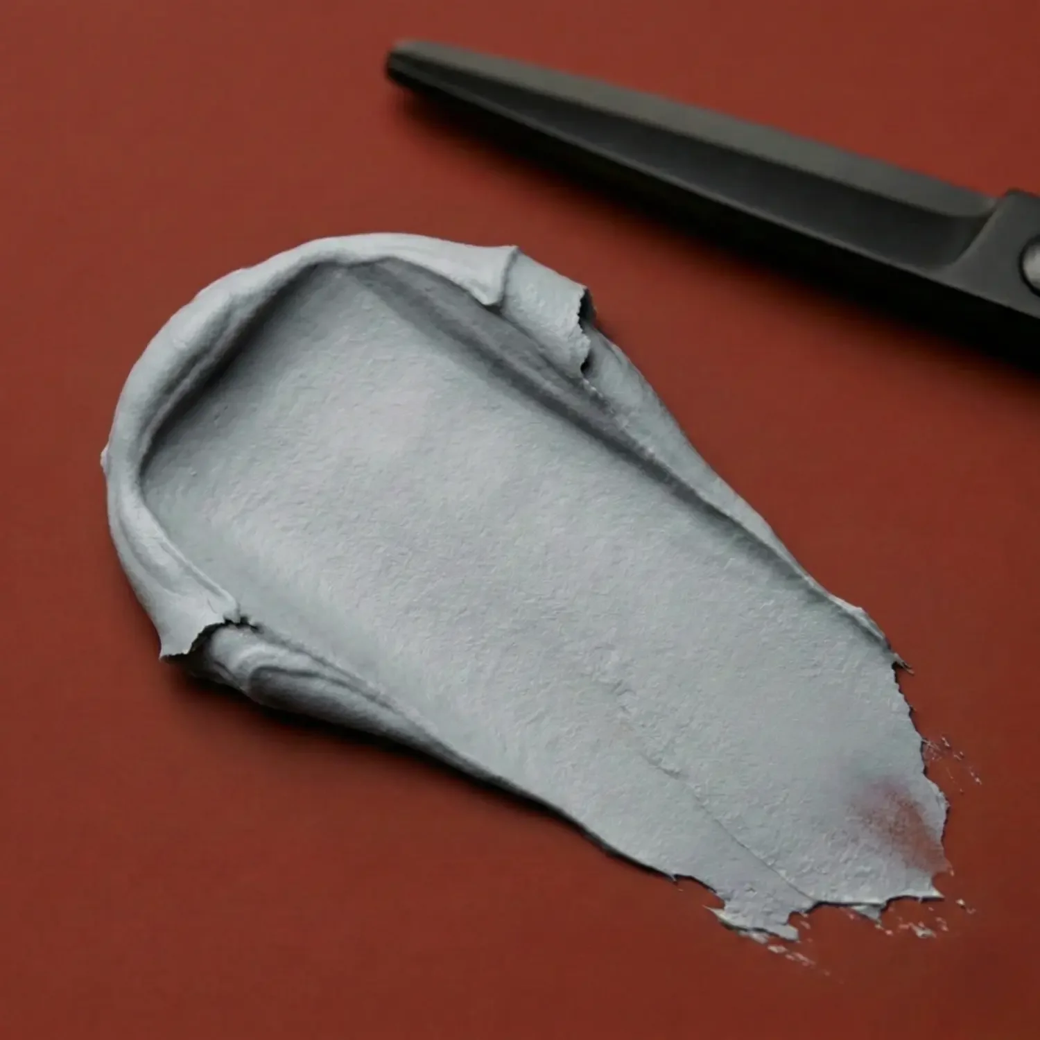 smudge-of-grey-hair-paste-on-light-brown-background.webp