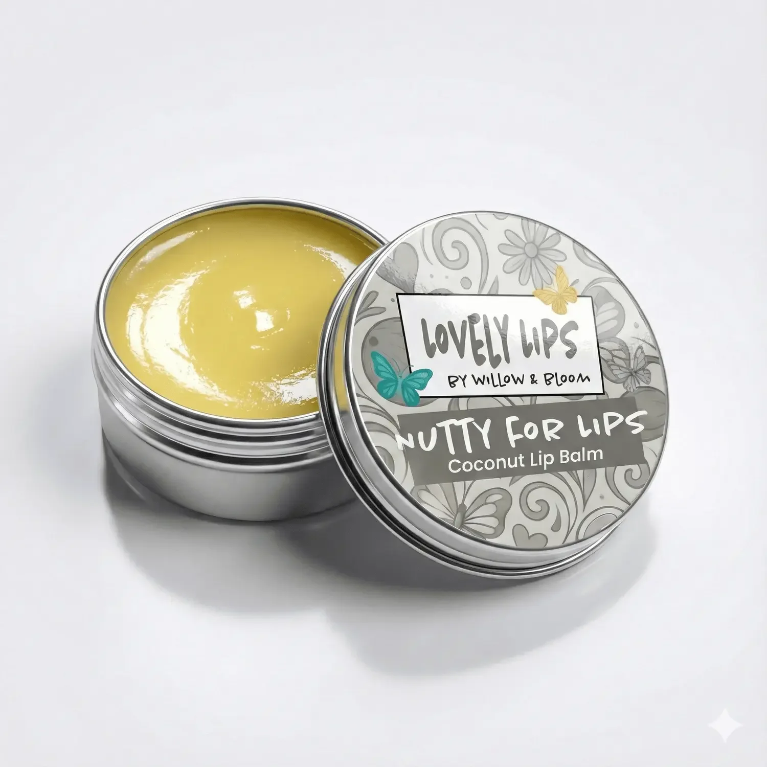 Open metal tin of yellow coconut lip balm with a decorative lid that reads "Lovely Lips by Willow & Bloom Nutty for Lips Coconut Lip Balm" and features colorful butterfly illustrations.