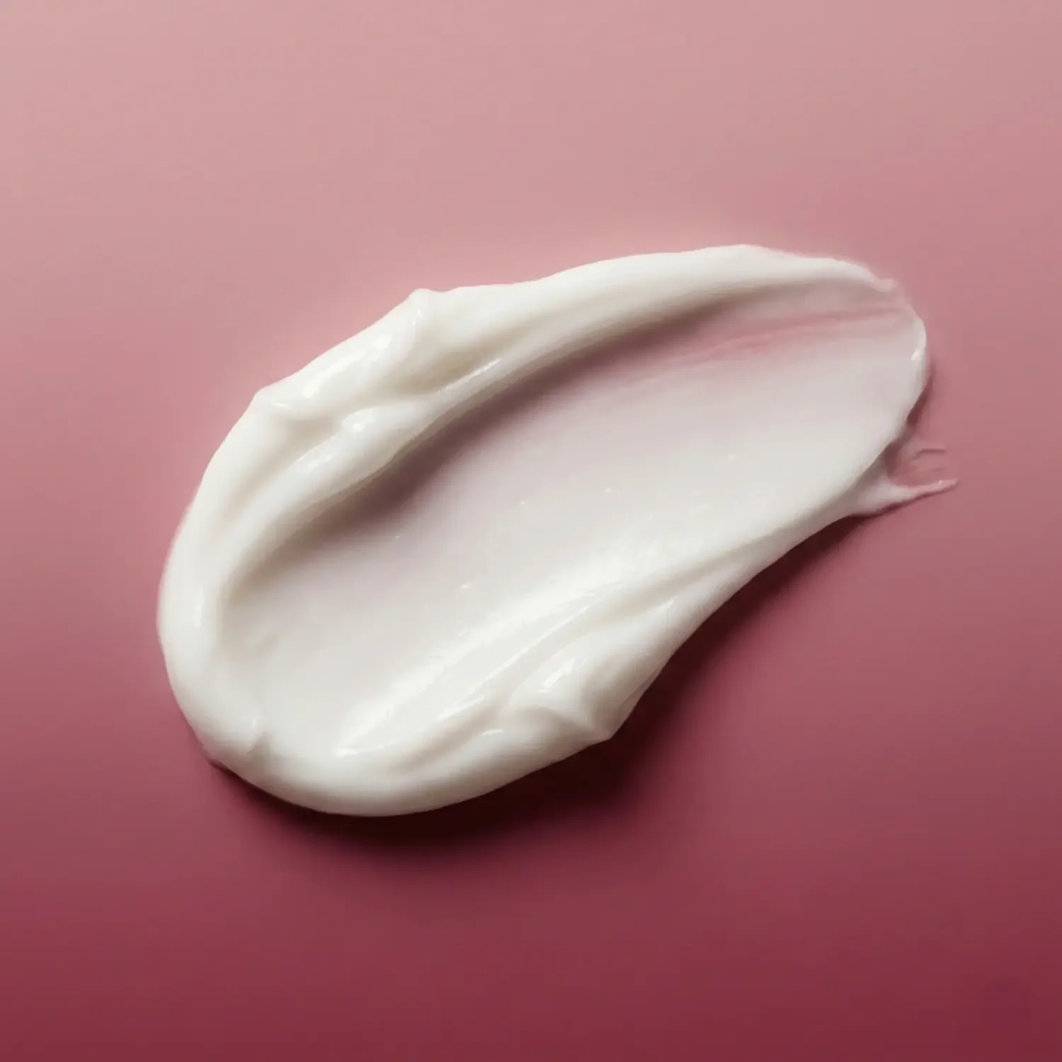 smudge-of-hair-cream-on-pink-and-rouge-gradient-background.webp