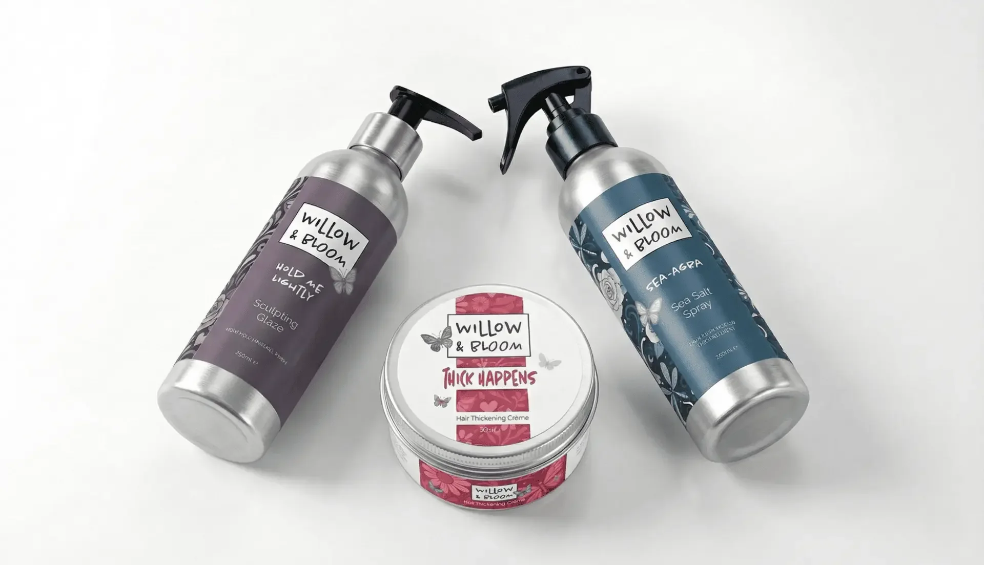 Three Willow & Bloom hair care products: a gray bottle labeled 'Hold Me Lightly Sculping Glaze,' a blue bottle labeled 'Sea-Agua Sea Salt Spray,' and a pink jar labeled 'Thick Happens Hair Thickening Crème,' arranged on a white surface.