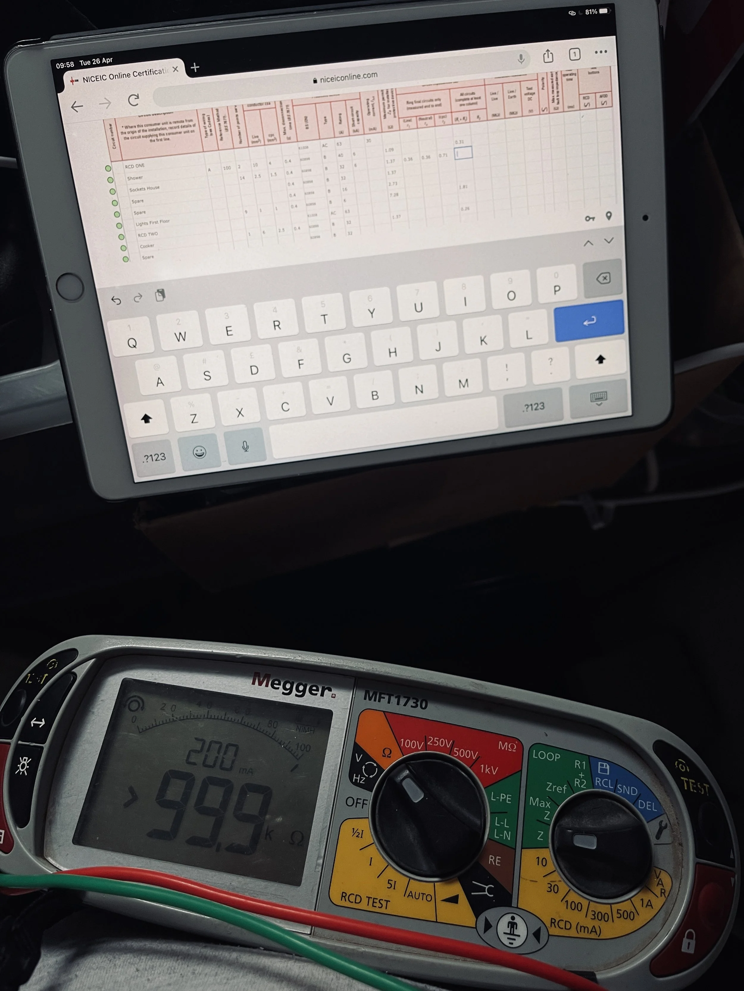 An iPad displaying a form or document and a digital multimeter showing a reading of greater than 994 ohms, with red and green test leads connected.