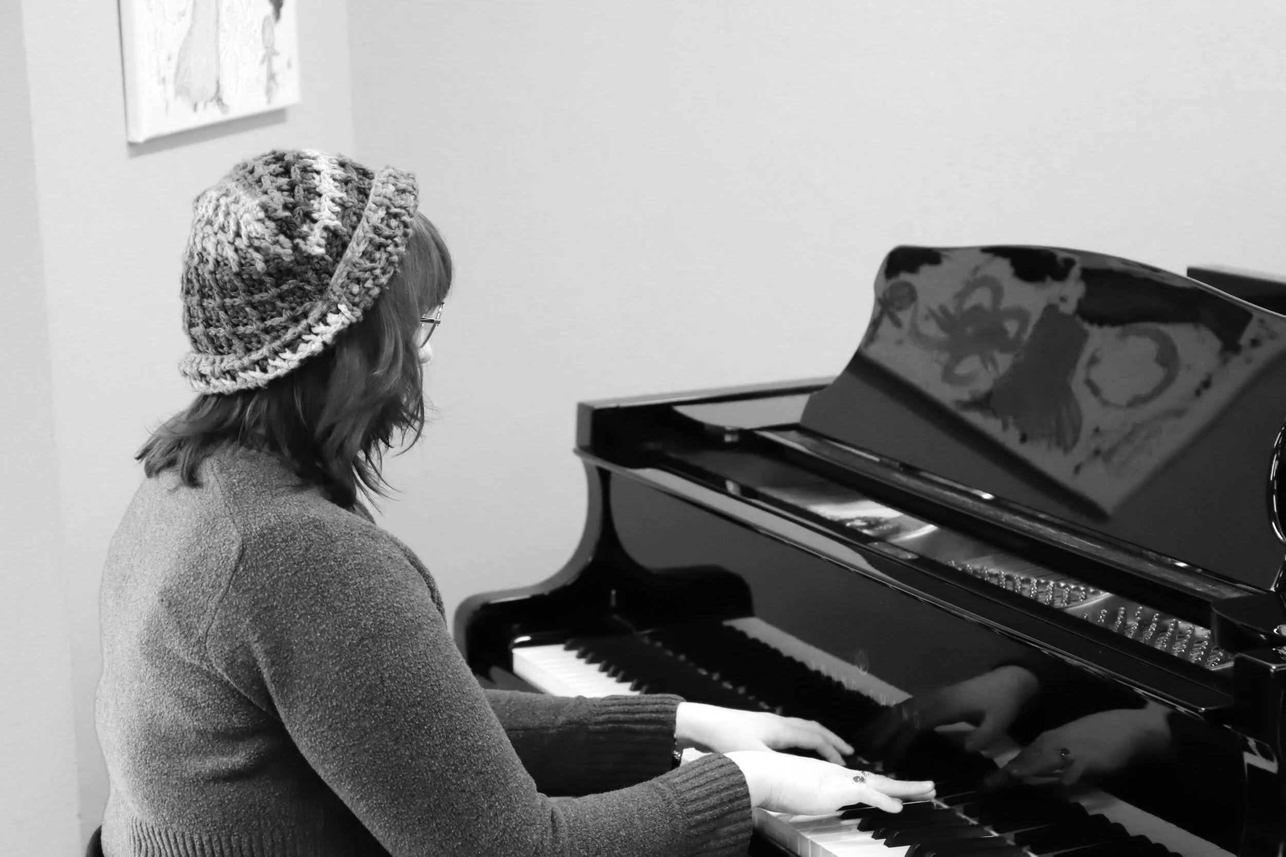 Candid side profile photo of Emma, NMTS music therapy intern, playing piano.