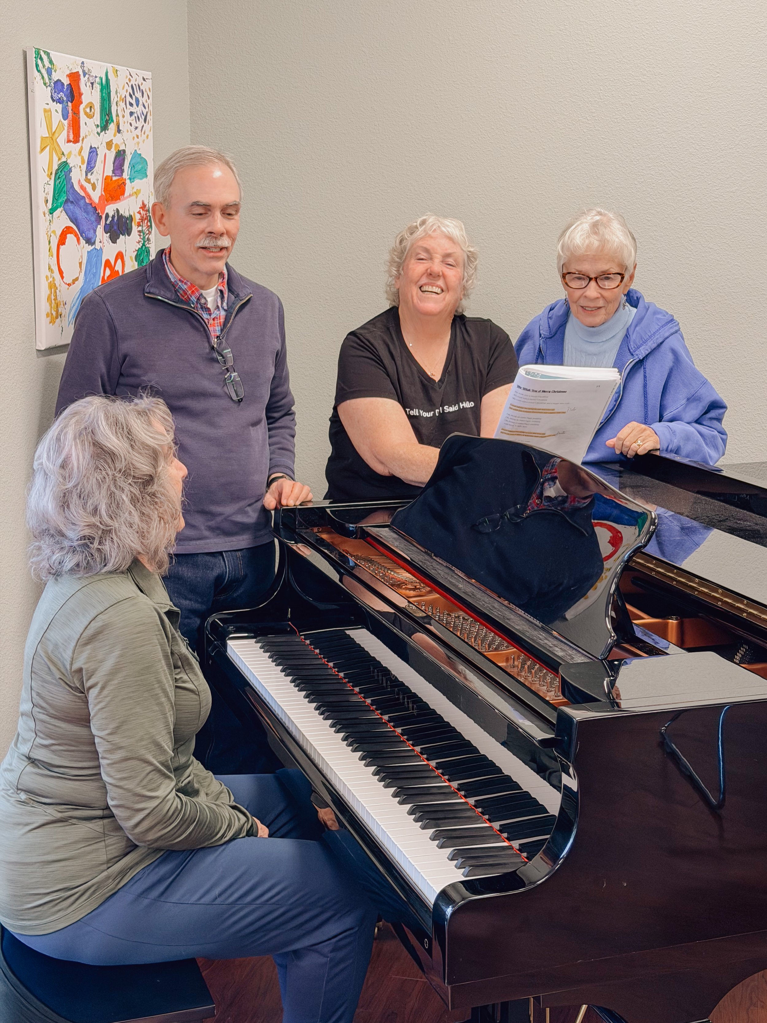 Group of older adults singing together around a piano at NMTS