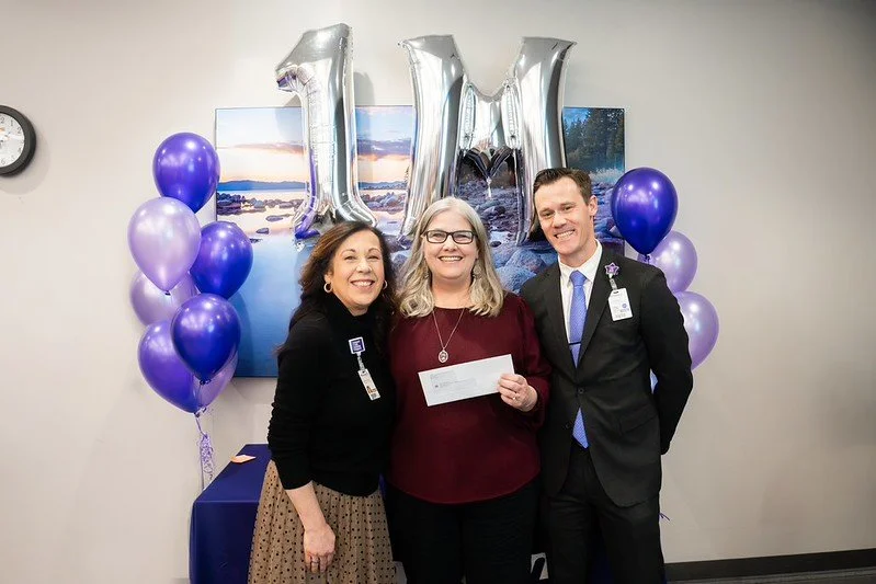 NMTS Executive Director Manal with two Renown Health representatives holding a check at a grant celebration