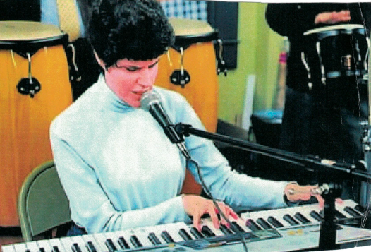 Jeanine Mooers playing piano and singing.