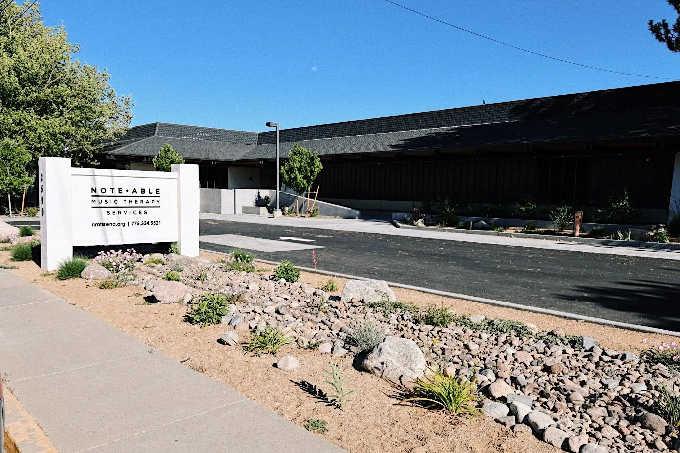 Photo of the front of Note-Able Music Therapy Services building with fresh pavement, landscaping, and a new sign.
