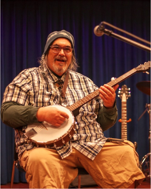 Photo of individual on stage at NMTS playing an instrument.