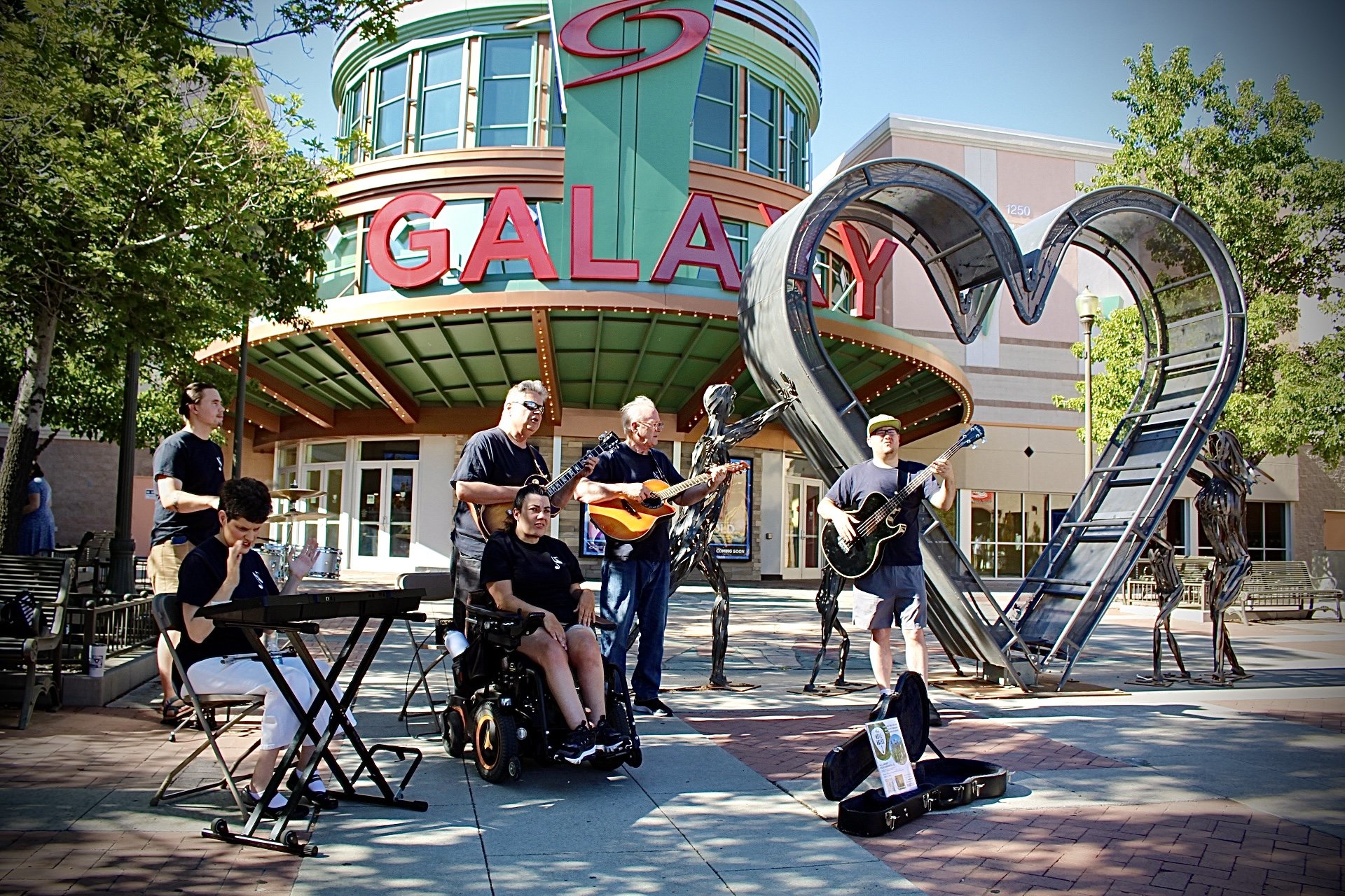 The Note-Ables band performing in front of a heart shaped sculpture.