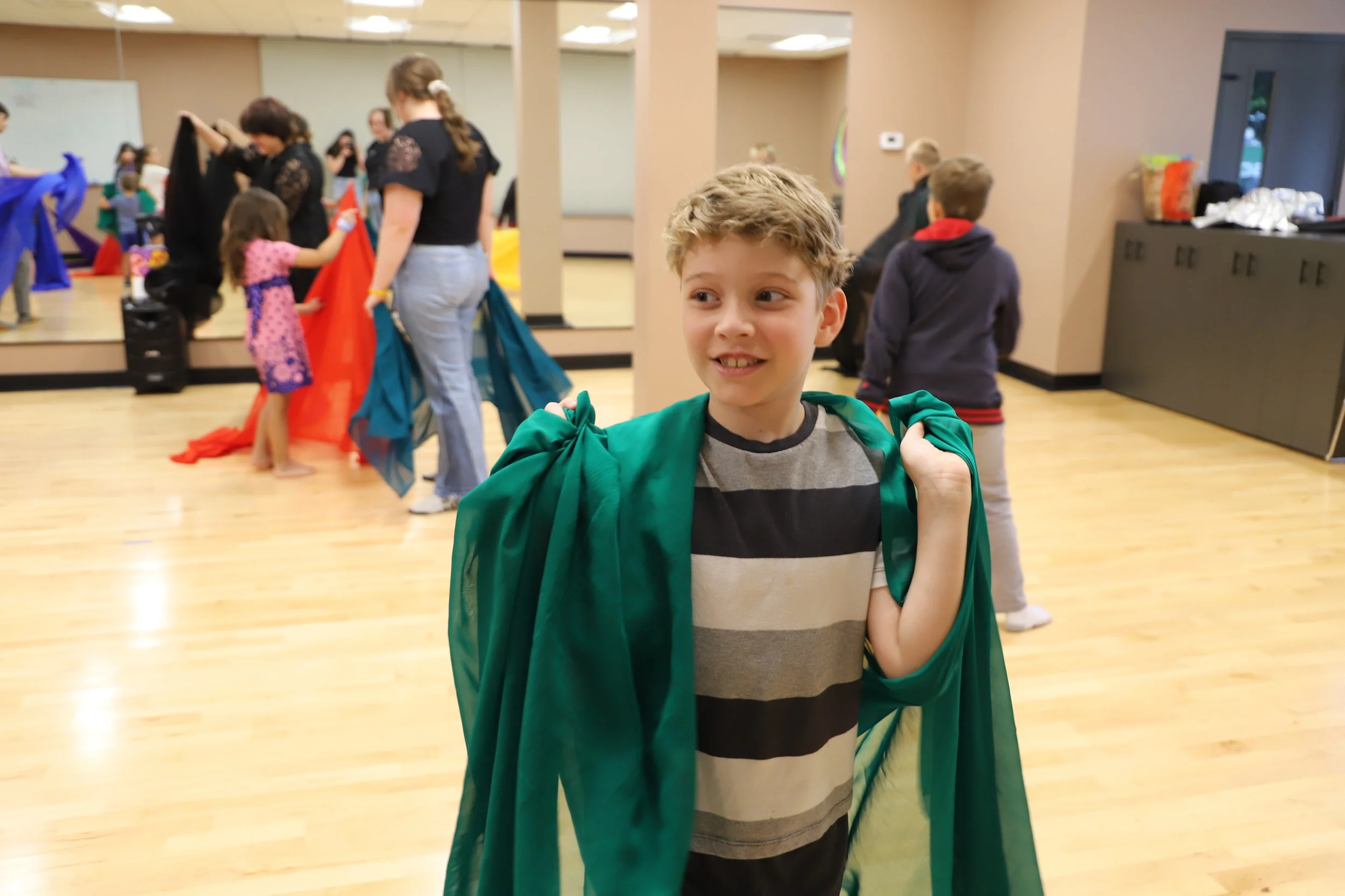 Kid holding a scarf around his shoulders during a dance centered activity at the 2025 kids summer music camp