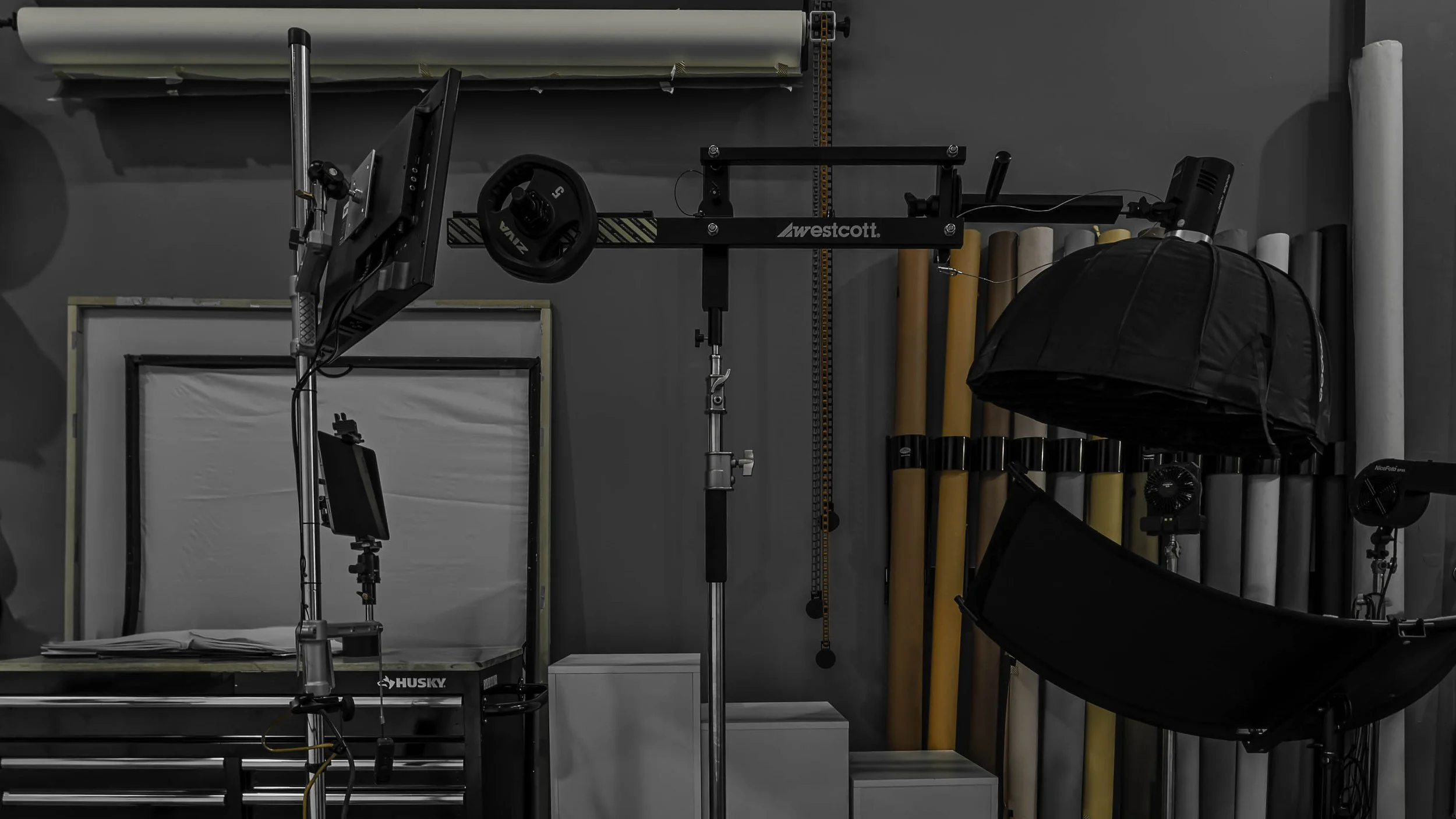 Photography studio setup with lighting equipment, a softbox, light filters, and rolling carts against a gray wall.