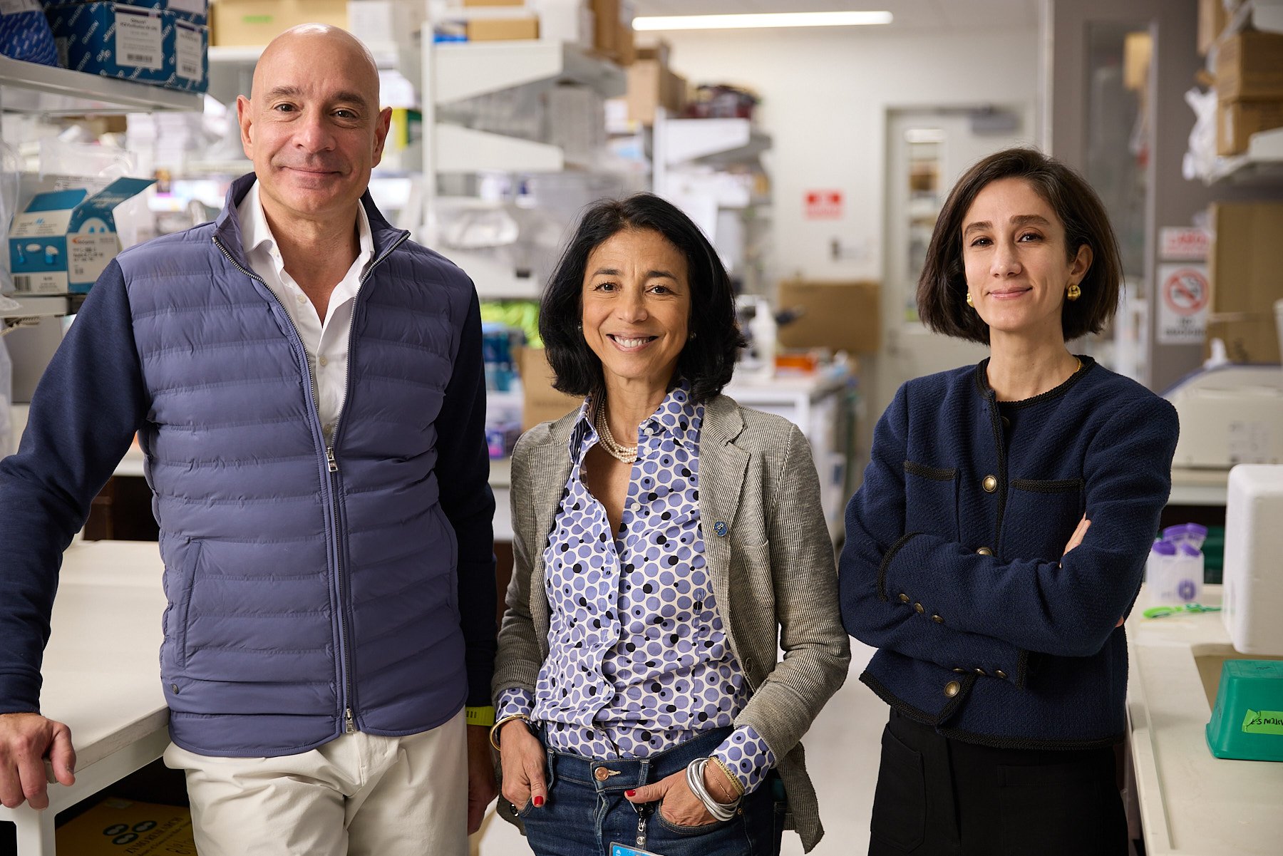 Three doctors, Zahi Fayad, Fanny Elahi, and Miriam Merad, standing side by side in a laboratory or medical setting, smiling at the camera. At Mount Sinai Hospital in New York City