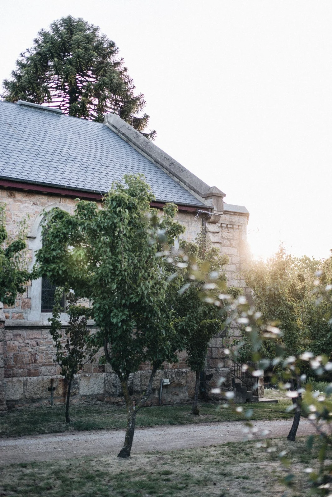 Sunset image of old stone church in Beechworth vines trees in front.