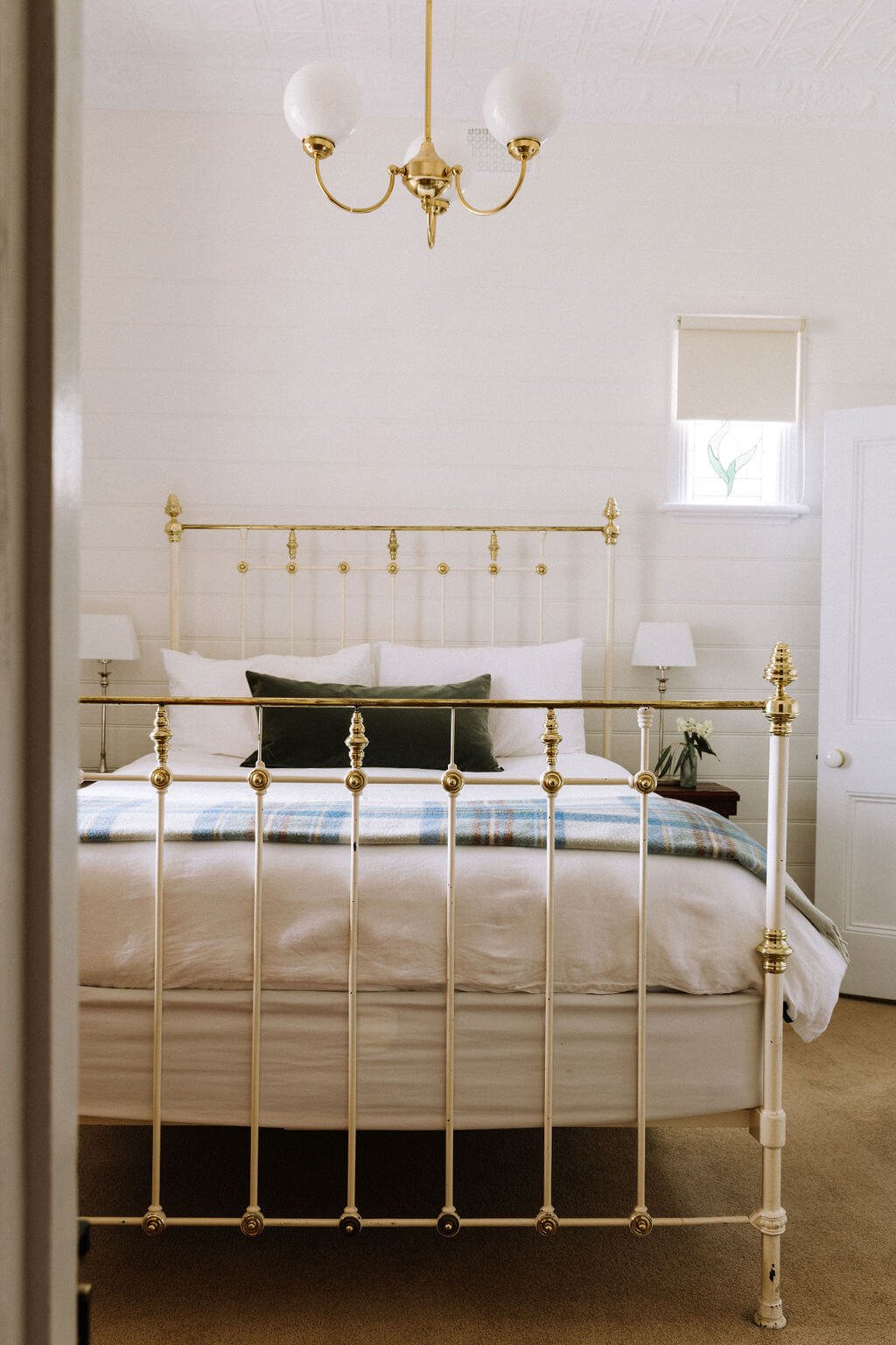 The Inn Beechworth, Luxury Accommodation - Kelly House. Vintage-style bedroom with brass bed frame, plush pillows, patterned blanket, and elegant chandelier.